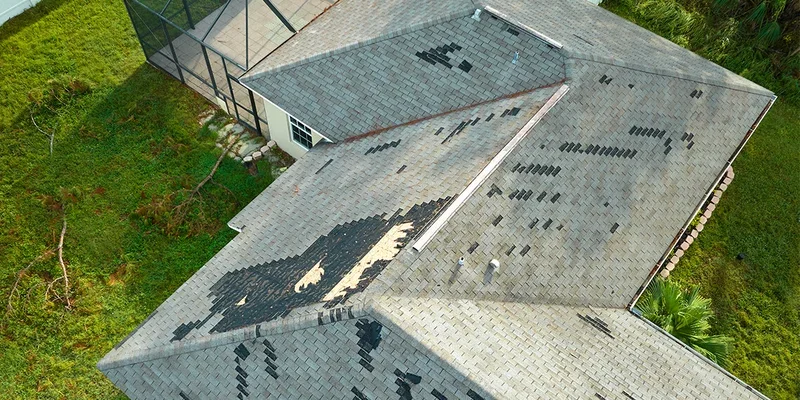 Aerial view of a house roof with damaged shingles and missing sections.
