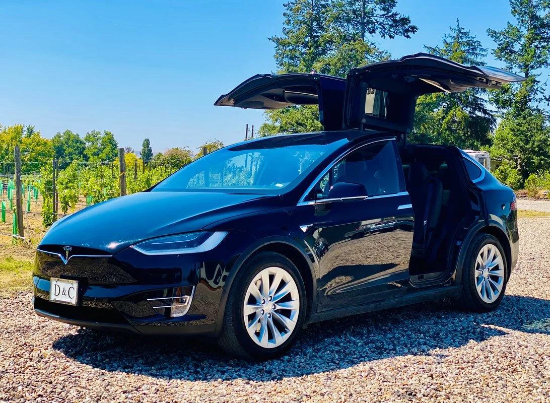 Black Tesla Model Y with gull-wing doors open, parked in  a vineyard in the Walla Walla Valley.