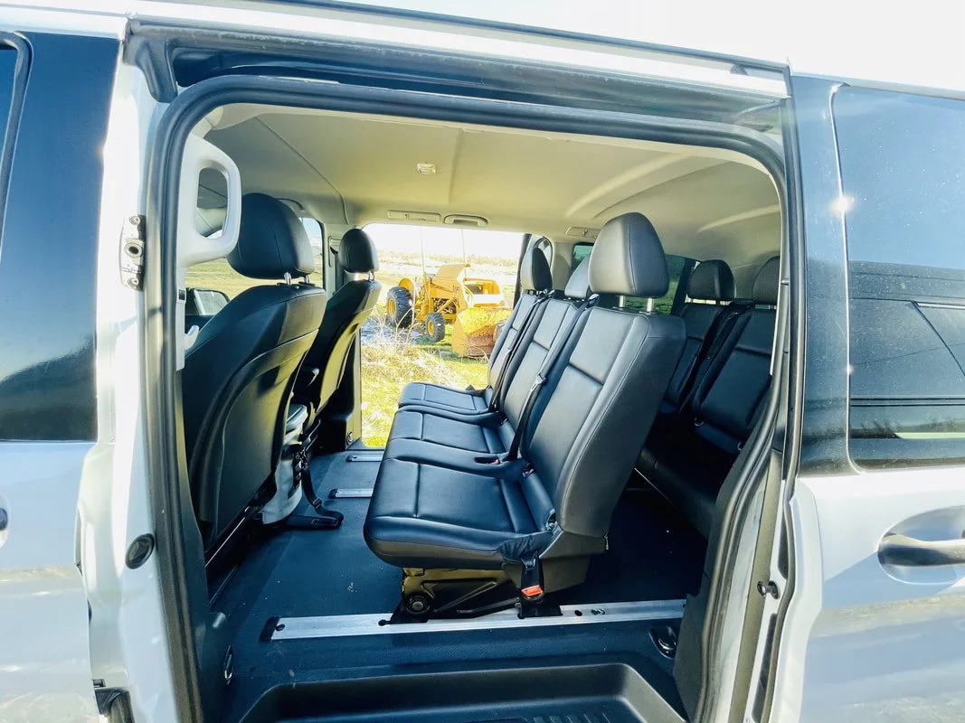 Interior of a black van with three rows of black leather seats, open sliding door, in Walla Walla.