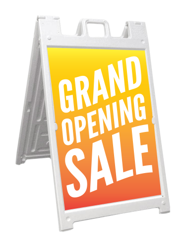 A sidewalk signboard with a yellow and orange background, announcing a grand opening sale.