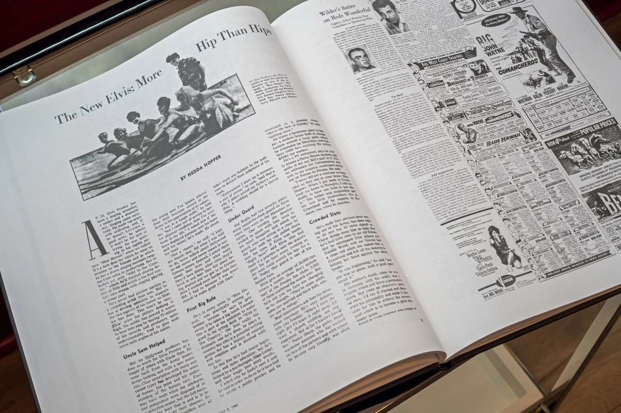 Open newspaper featuring an article titled 'The New Elvis: More Hip Than Hips' with a black-and-white photo of women in swimsuits at the top of the left page, and various advertisements on the right page.