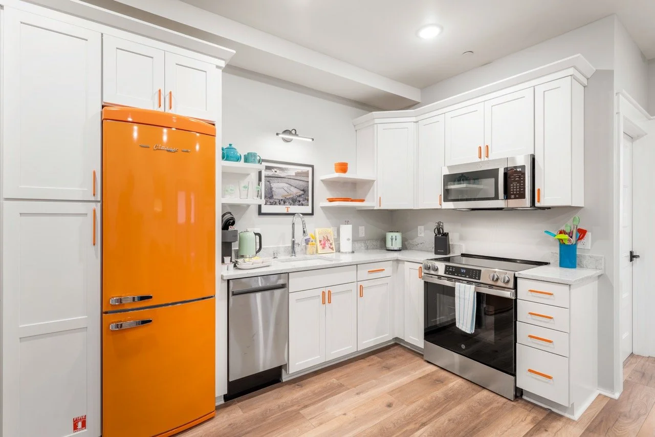 Orange refrigerator in clean white kitchen