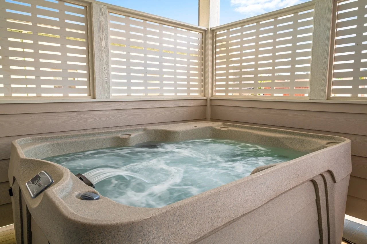 An outdoor hot tub with bubbling water, enclosed by a wooden privacy fence.