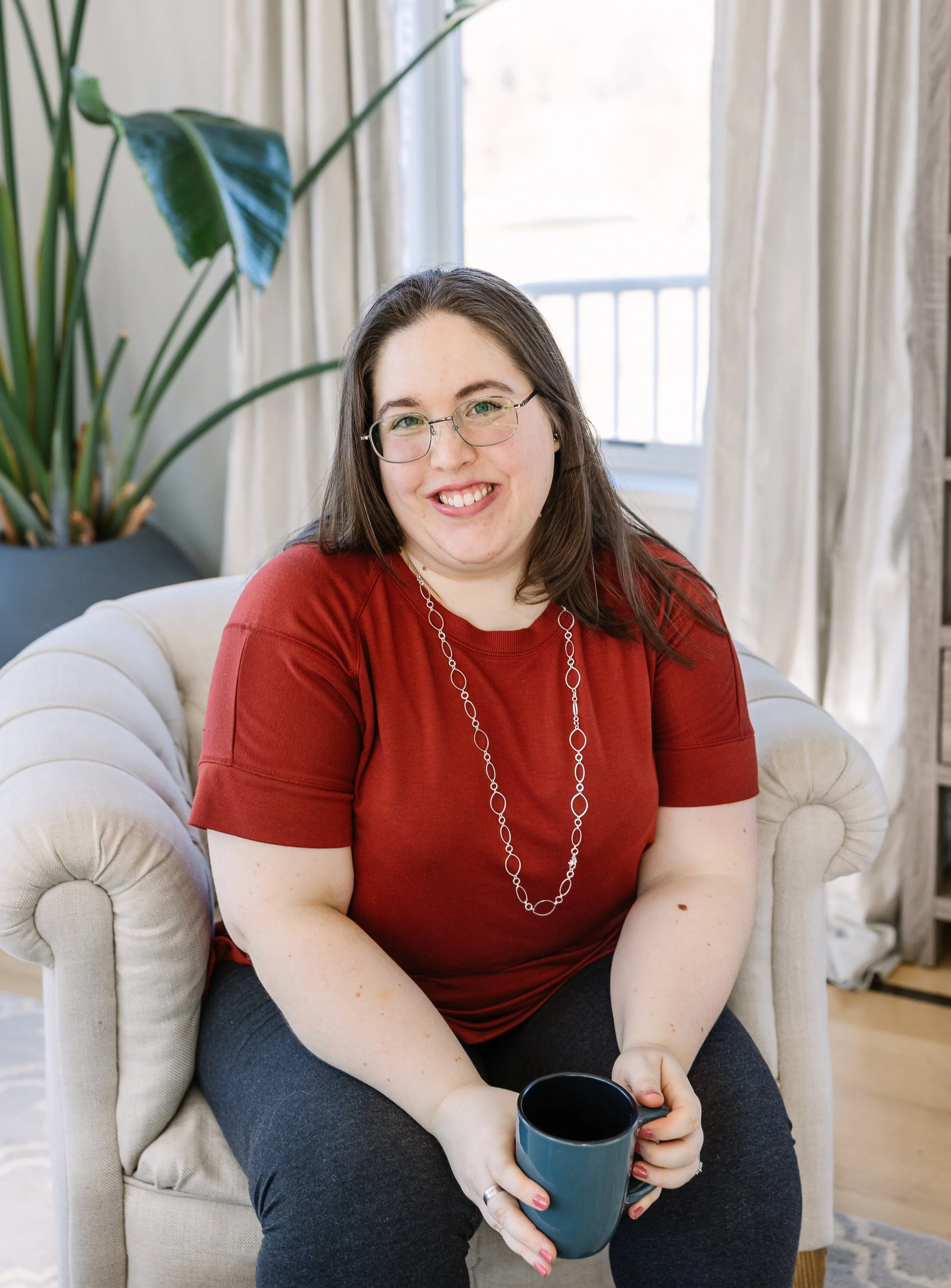 Professional speaker Sarah LaFontaine sitting on chair holding mug