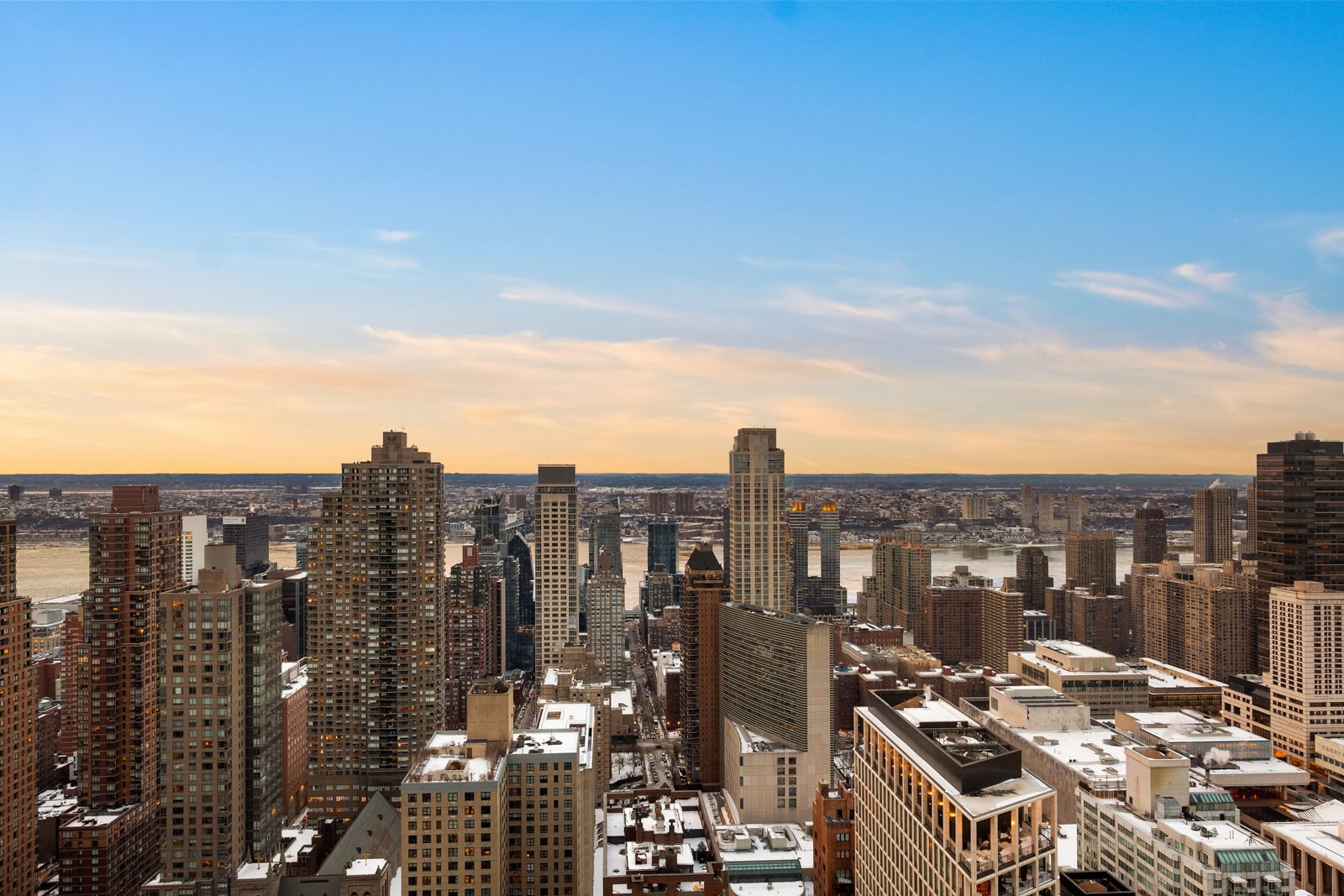 A city skyline with tall buildings under a partly cloudy sky during sunset.