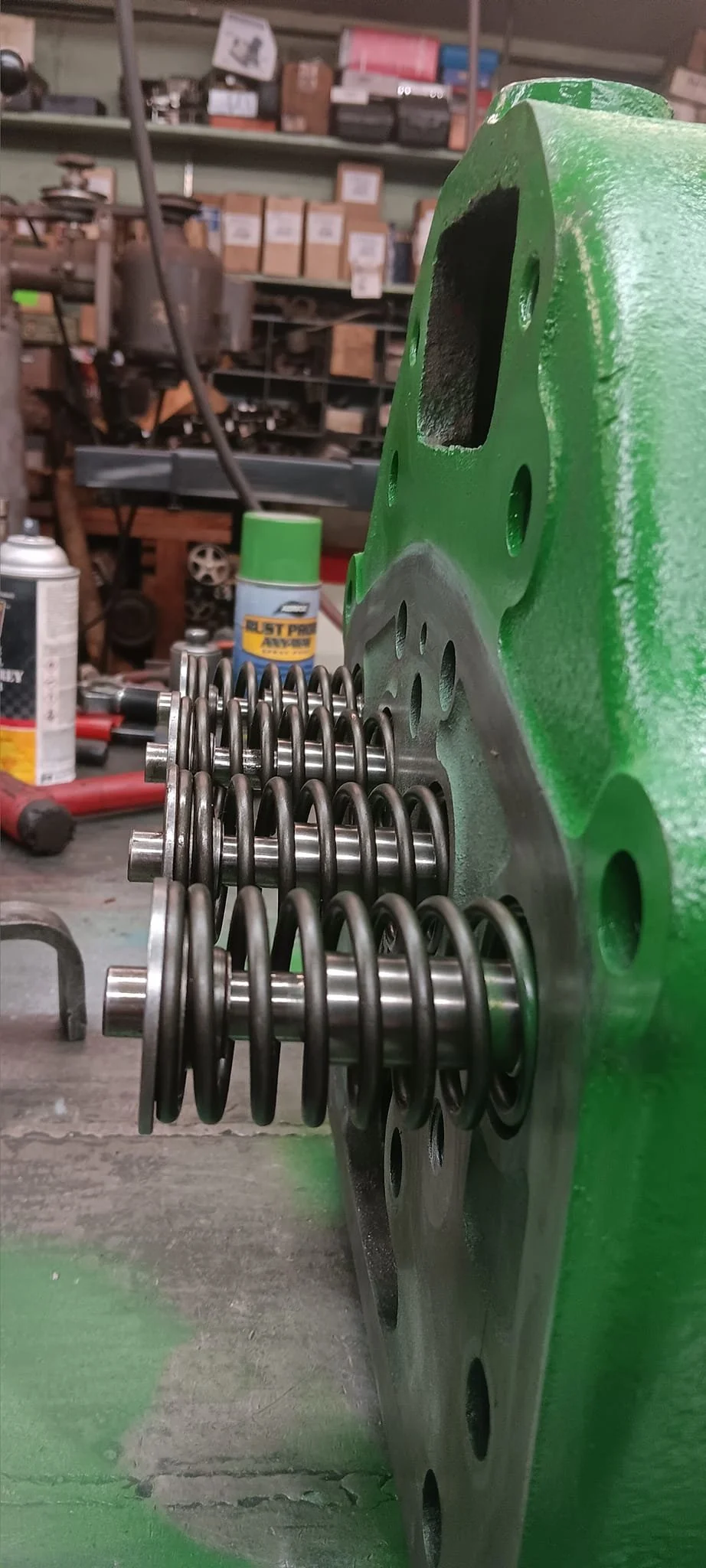 Close-up view of engine valve springs installed in a green engine block in a workshop.