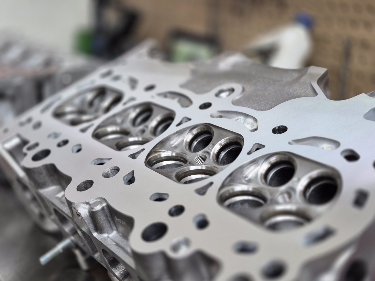 Close-up of a machined engine cylinder head with multiple valve seats and ports.
