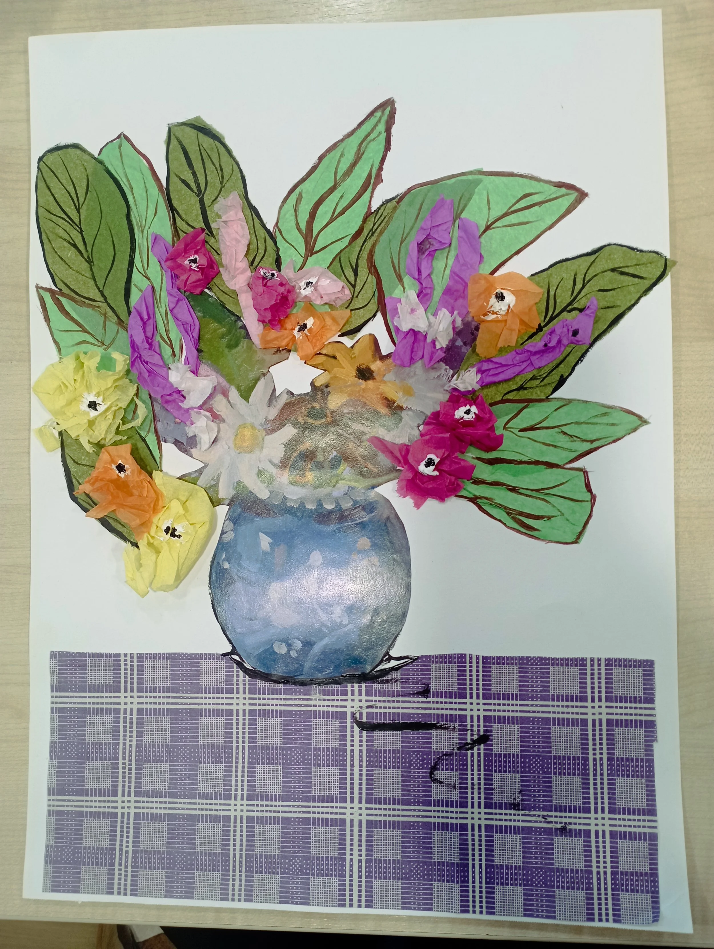 Colorful hand-made paper collage of a flower arrangement in a blue vase on a table.