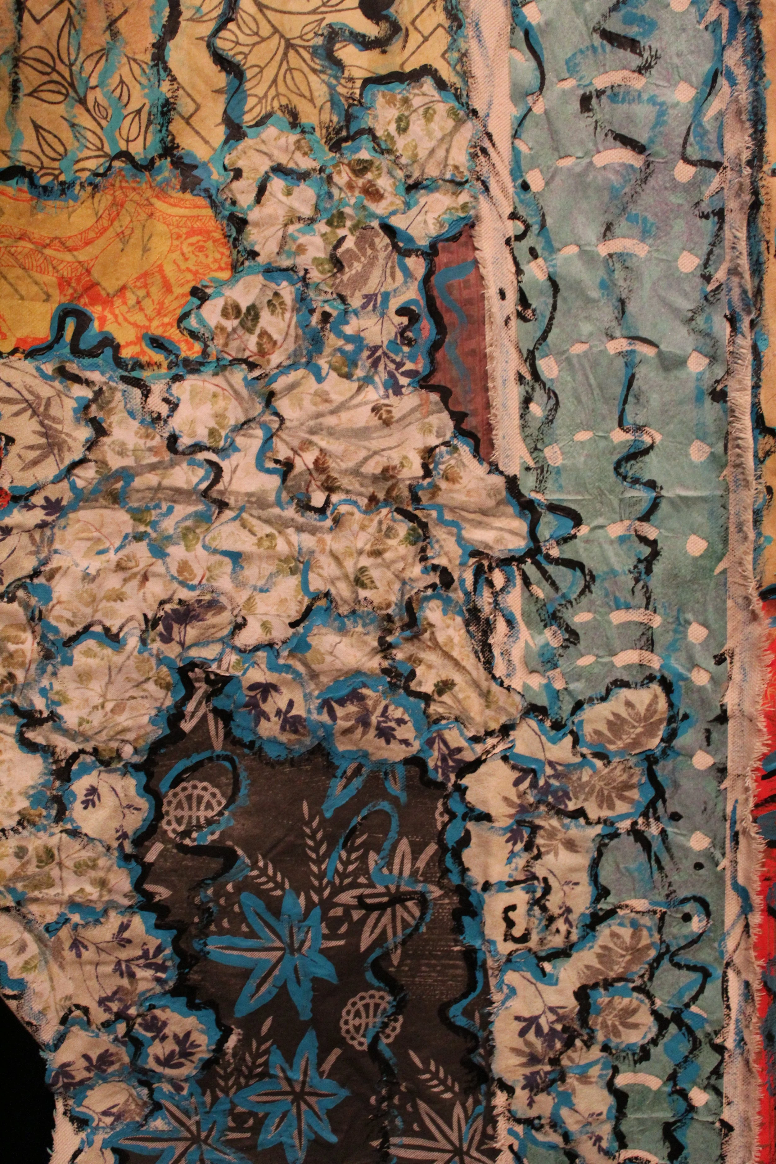Colorful quilt with various floral and abstract patterns in shades of blue, beige, black, and red.