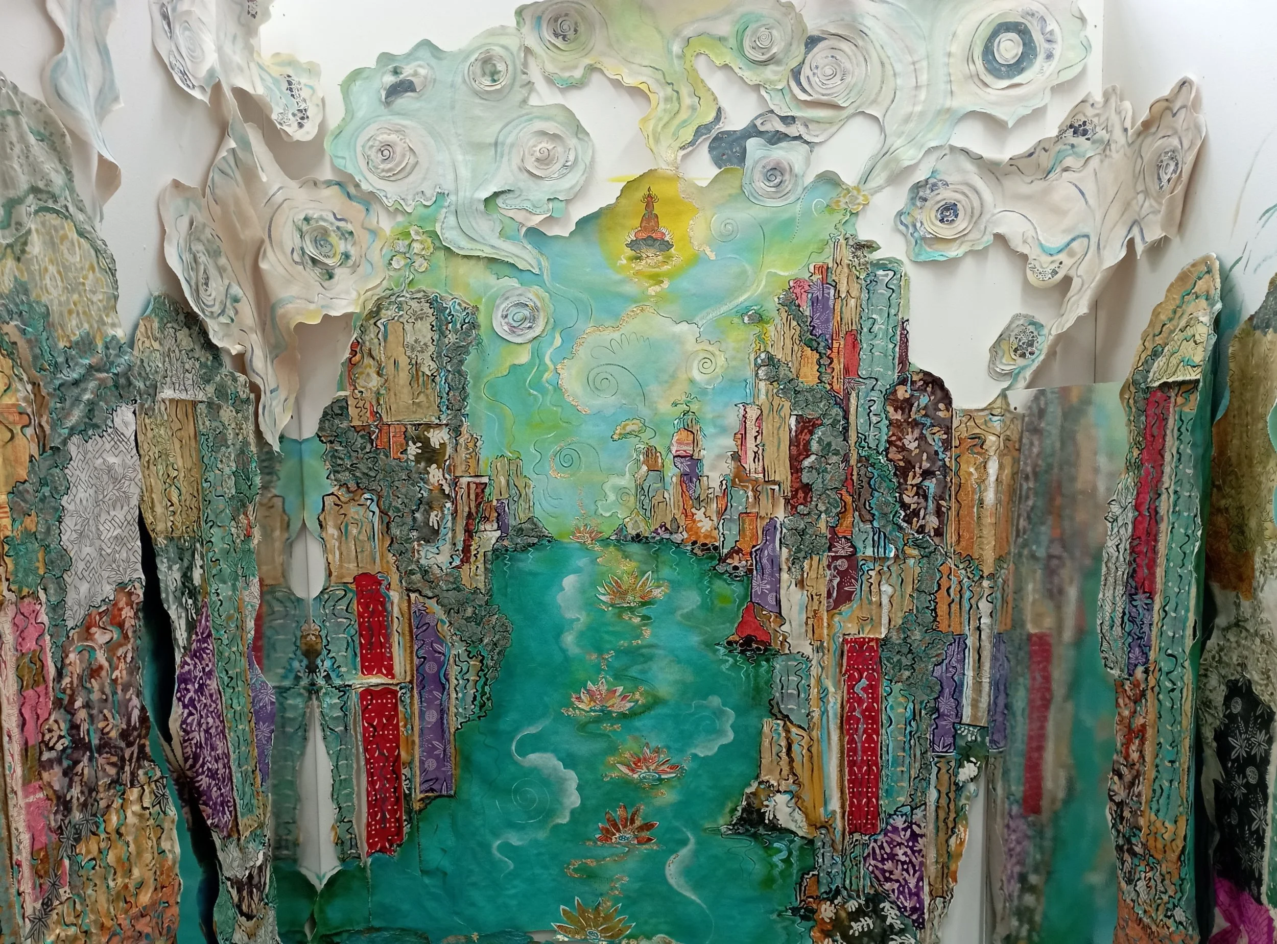 Colorful 3D paper art depicting a river flowing between mountains with a bright sky and swirling clouds above.