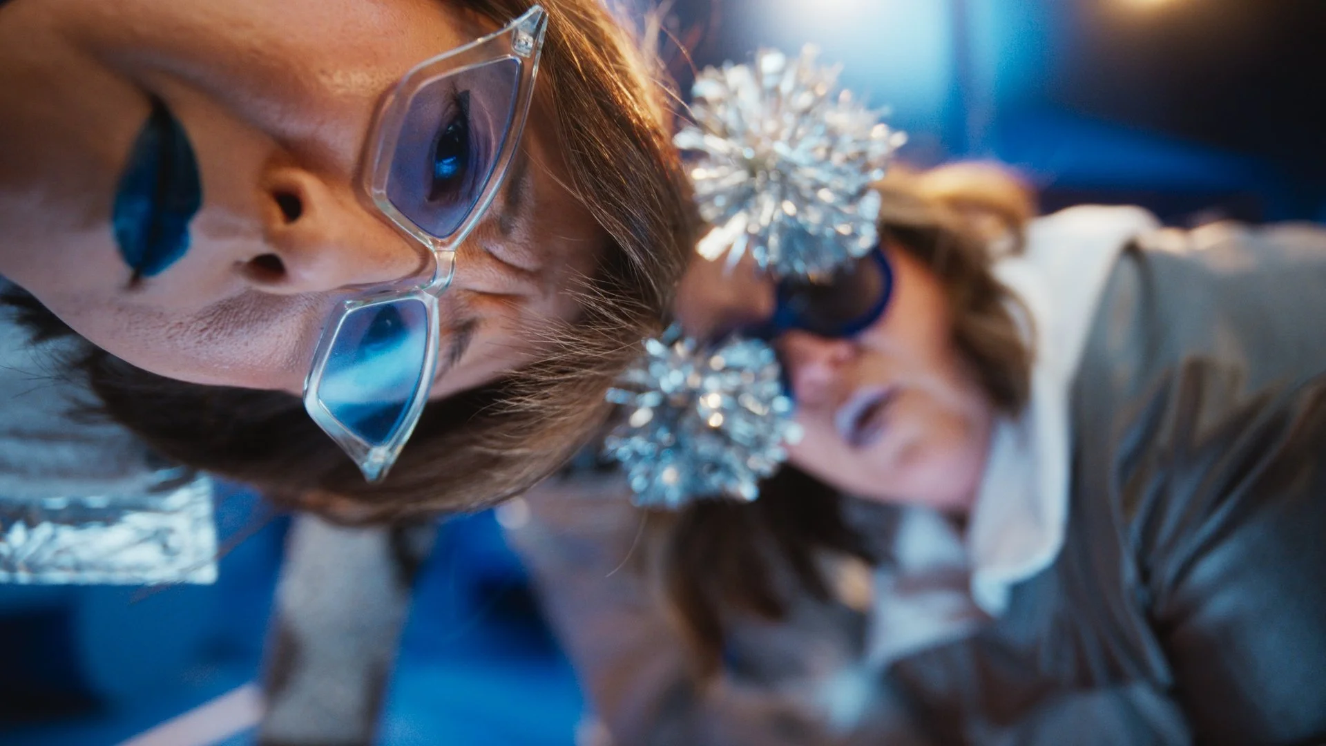 People wearing glasses with tinsel on their heads, celebrating at a festive event.