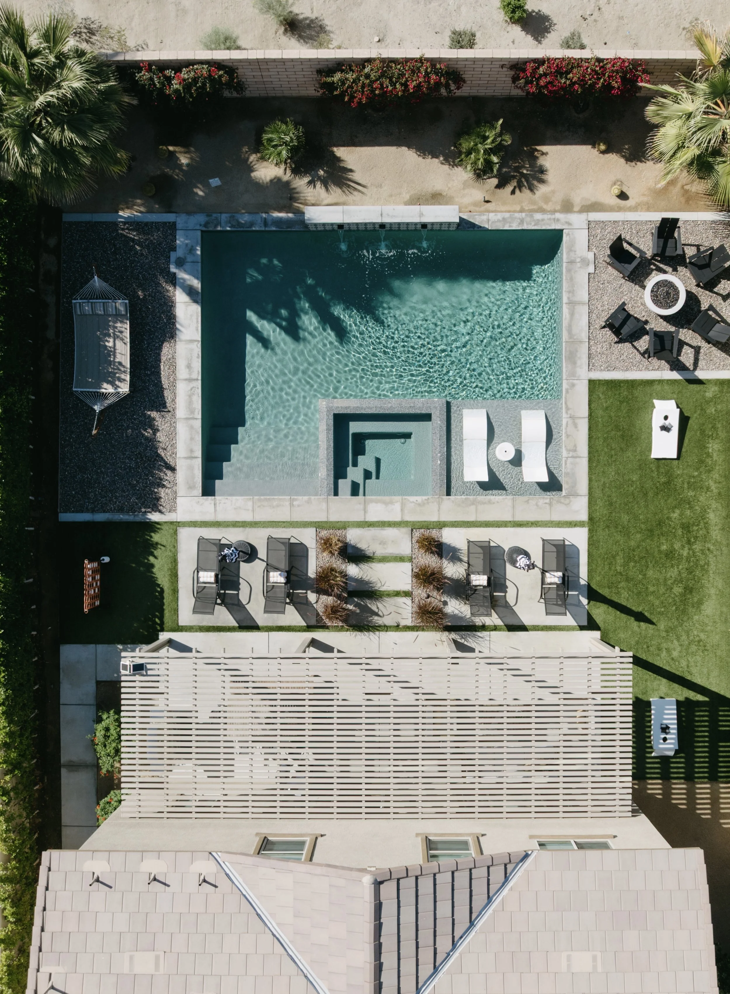 Aerial view of a backyard with a swimming pool, lounge chairs, a shaded hammock, trees, and a surrounding fence.