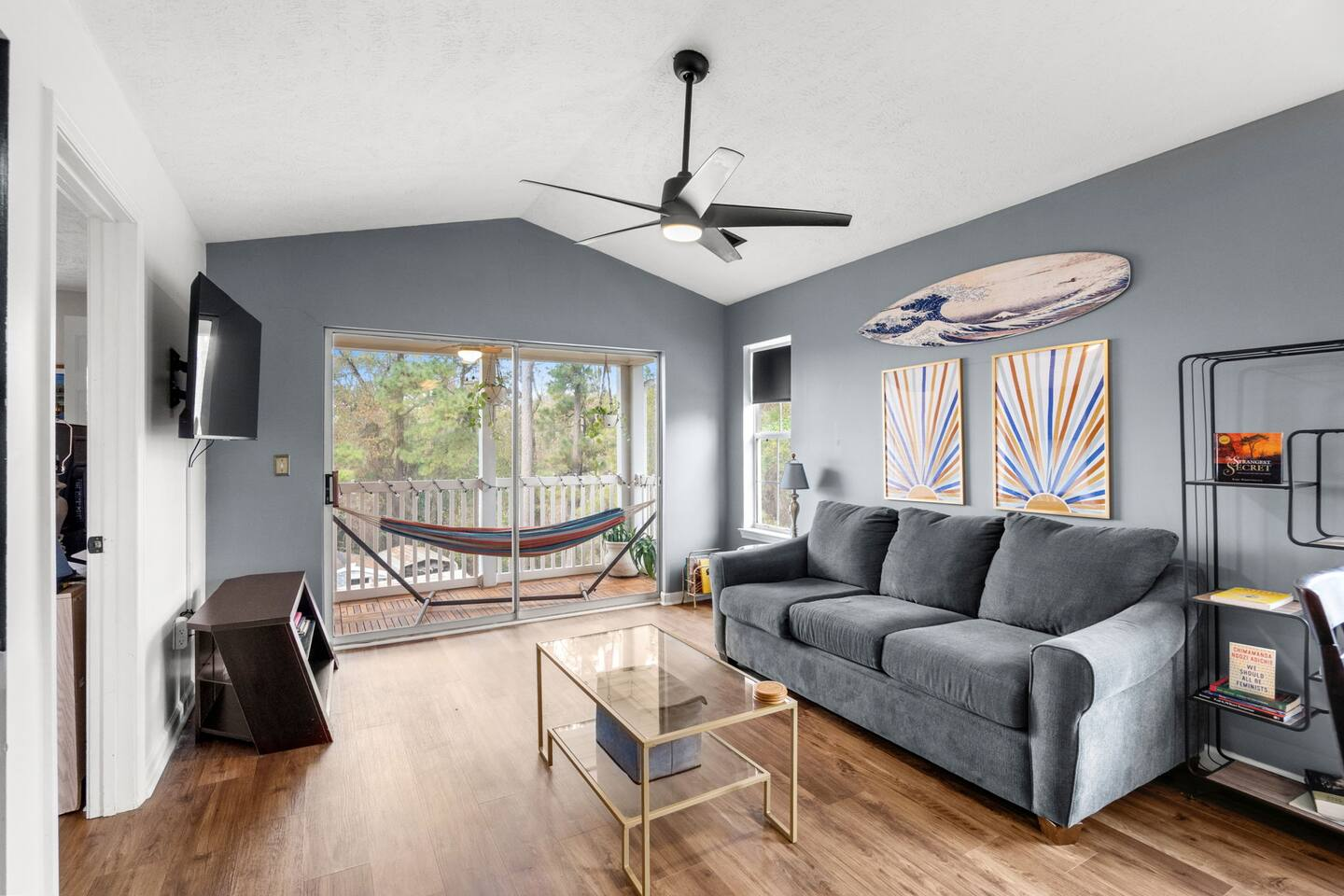Living room inside a Myrtle Beach SC rental condo at Waterway Village with gray sofa, modern artwork, and balcony with hammock.