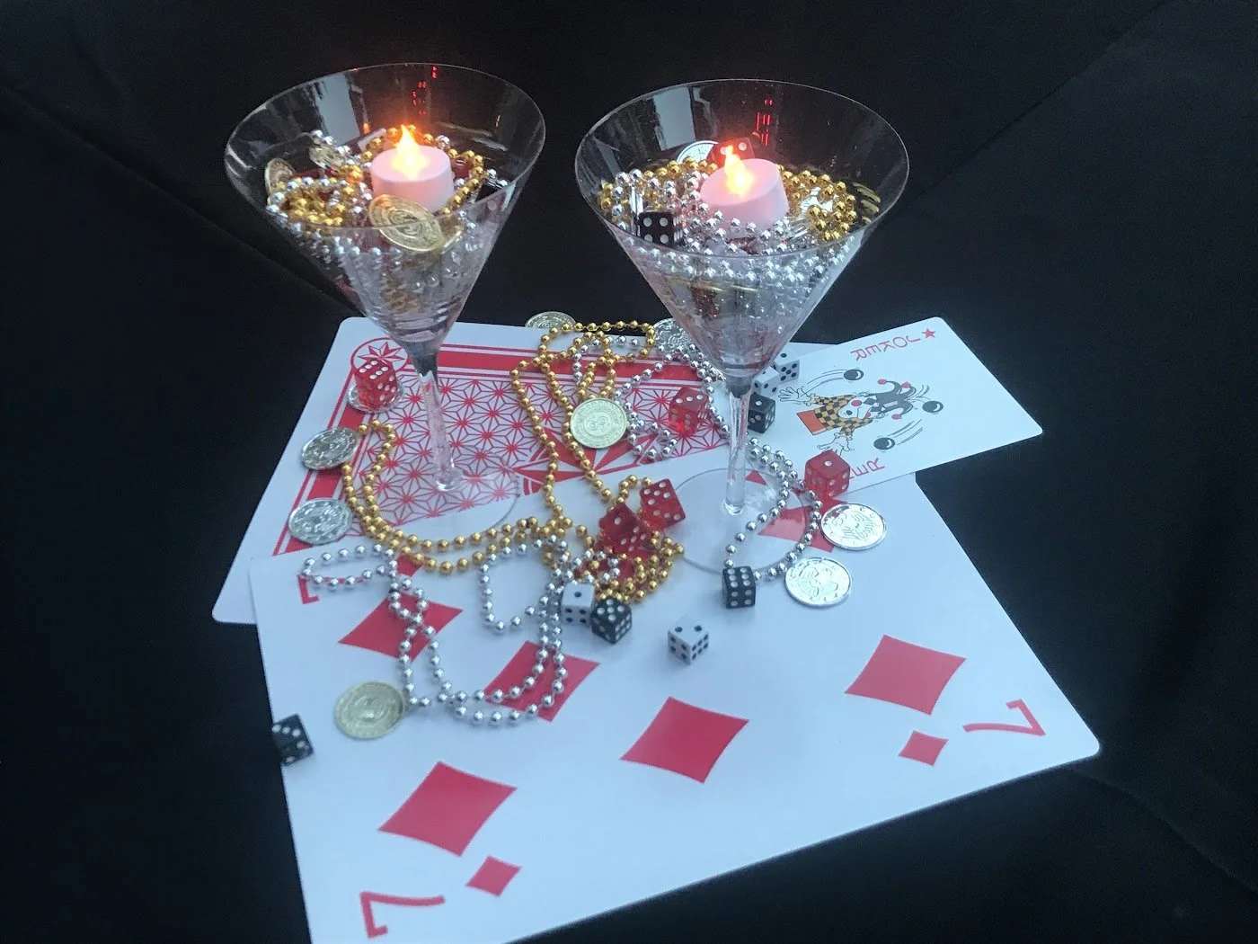 Casino event centerpiece set up featuring martini glass hurricanes, playing cards and poker chips with dice