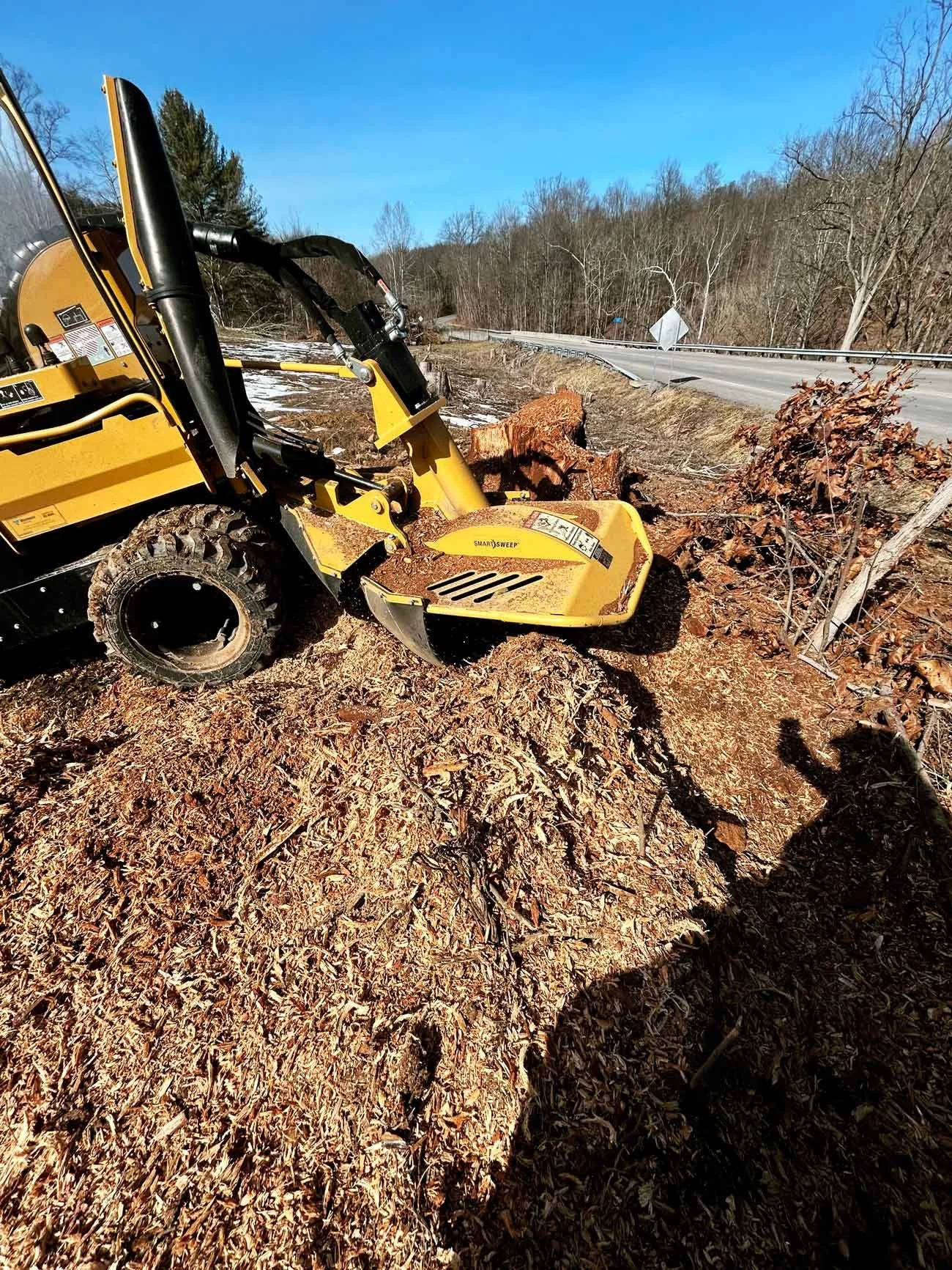 Commercial equipment clearing yard area after stump grinding and debris removal.