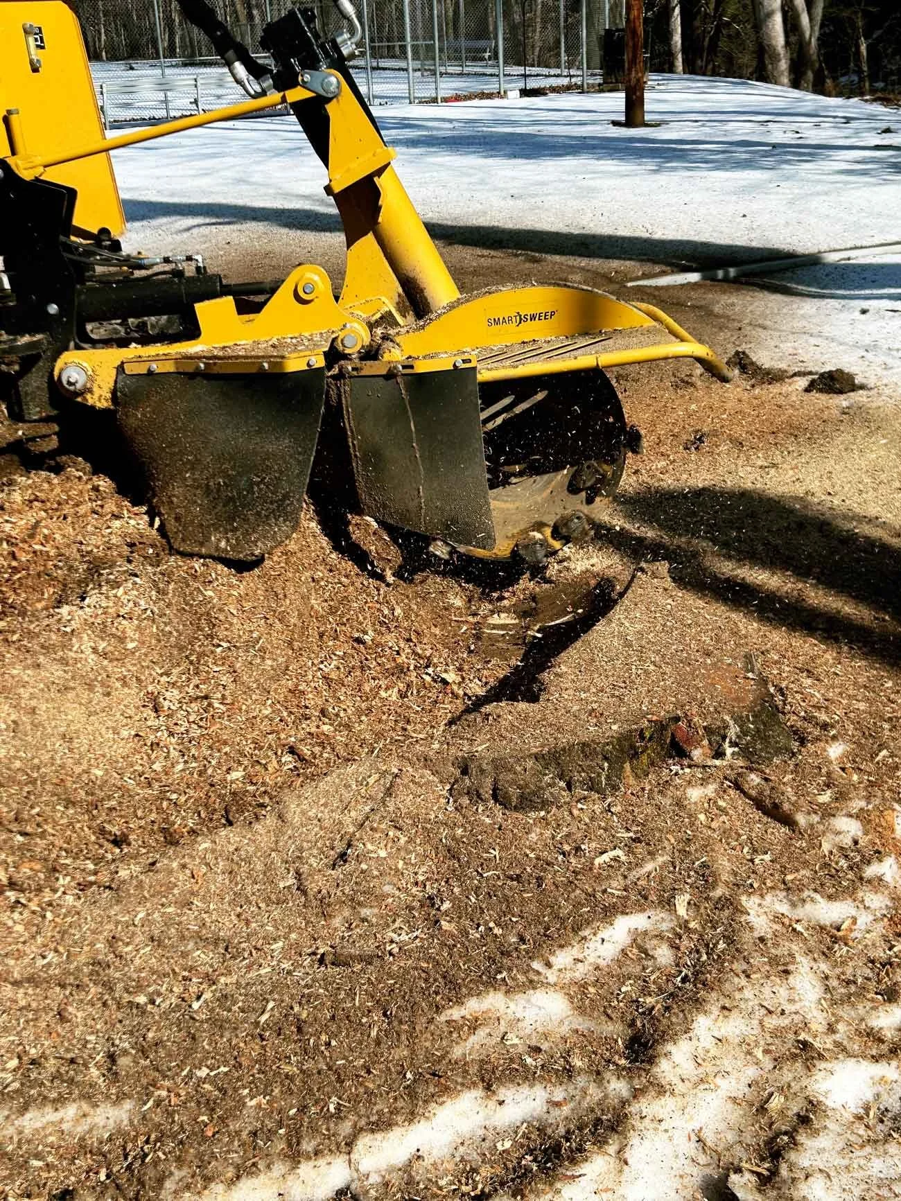 Contractor operating stump grinder to remove tree stump below ground level