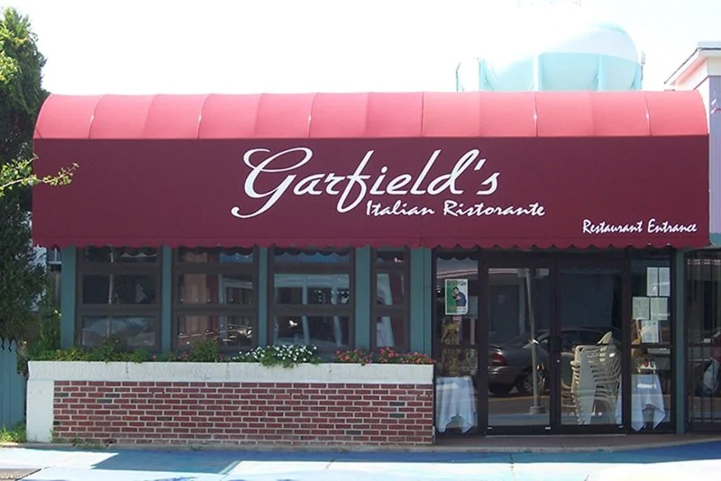 Exterior of Garfield's Italian Ristorante with a red awning, large windows, and outdoor seating.