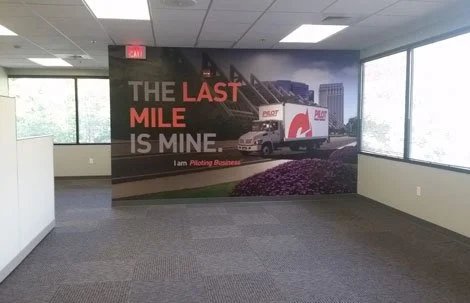 Office interior with a large wall mural of a moving truck and the text 'The last mile is mine'.