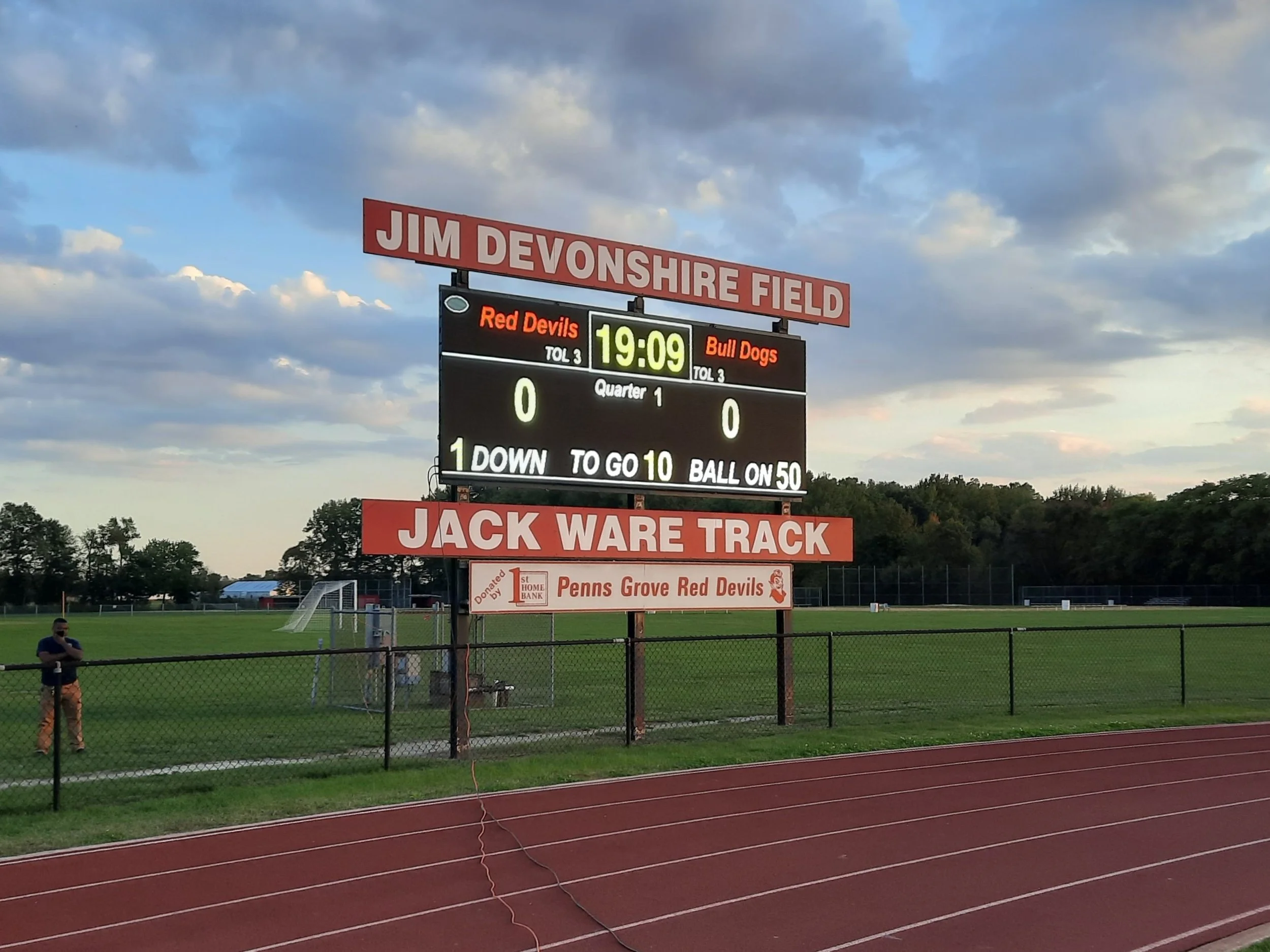 A digital scoreboard at Jim Devenshire Field displaying the score tied at 0-0, with 19:09 remaining in the first quarter, and showing the teams Red Devils and Bull Dogs.