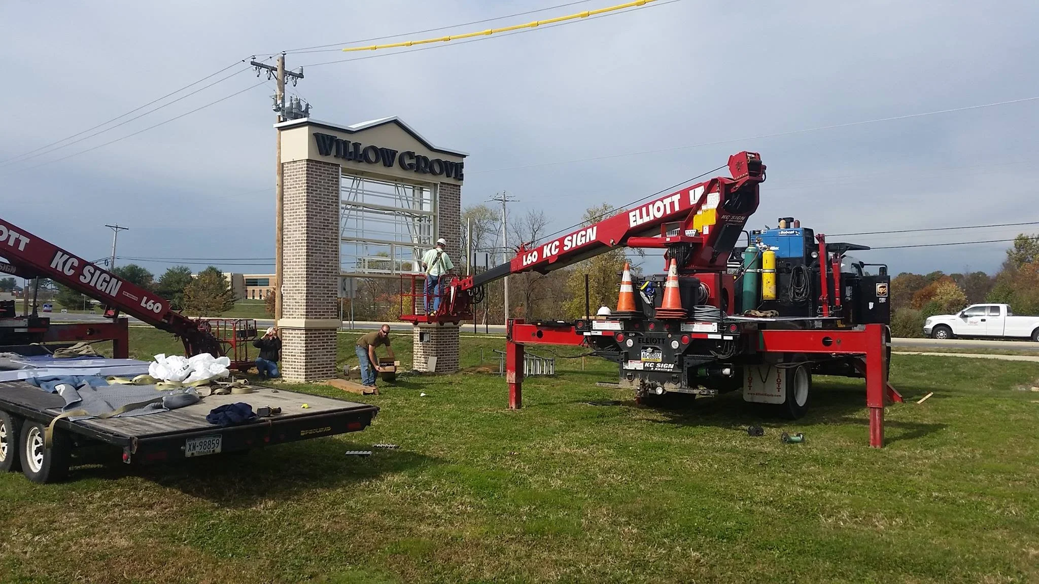 Workers installing a sign at the Willow Grove entrance using a crane with the sign framed but not yet mounted.