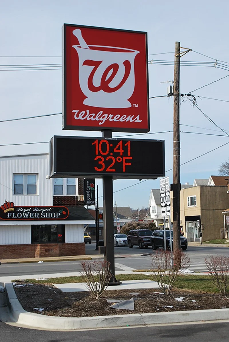 Walgreens store sign with the Walgreens logo featuring a white mortar and pestle with a 'W', displaying the time 10:41 and temperature 32°F on a black digital screen.