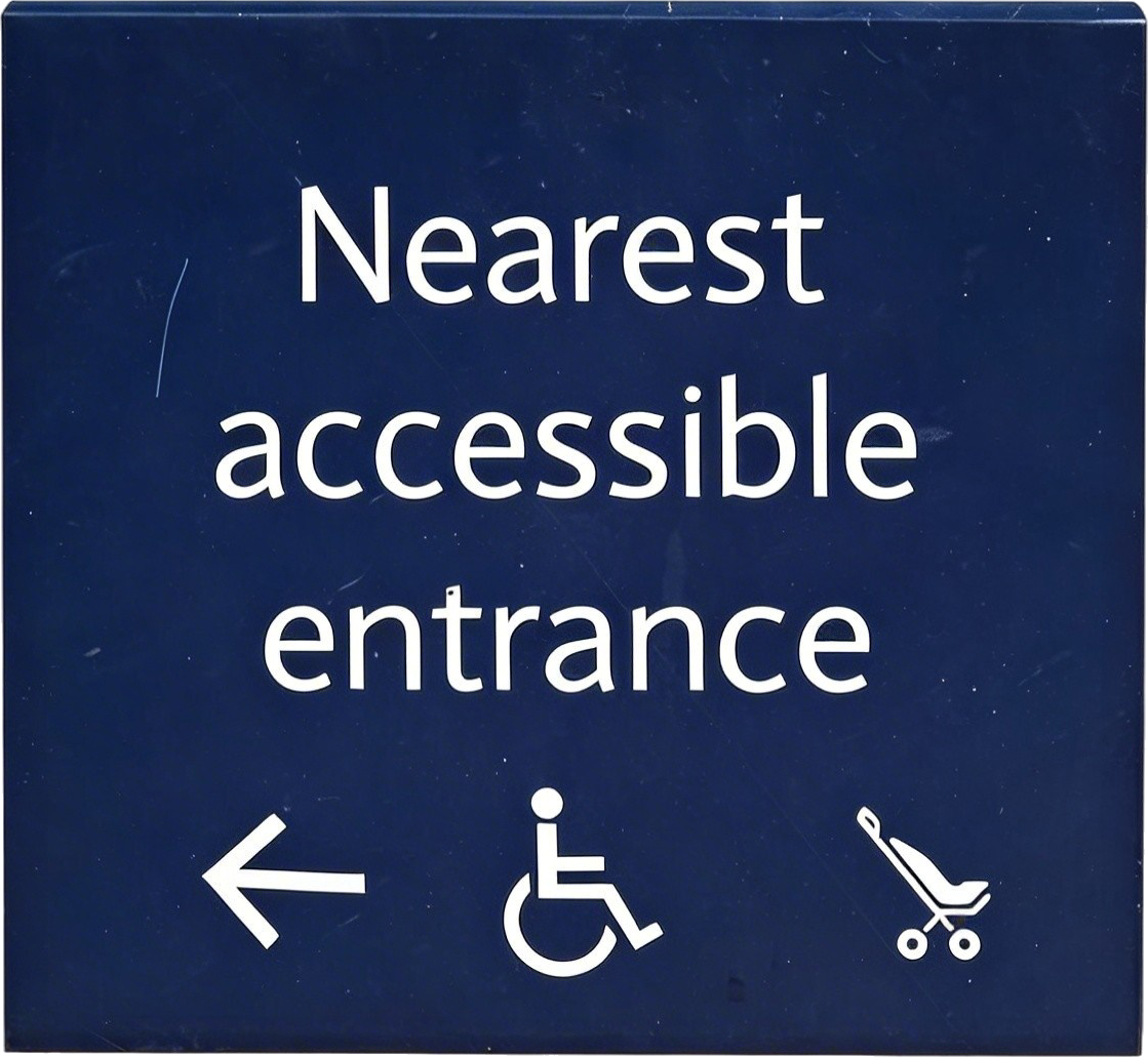 Sign indicating nearest accessible entrance with a left arrow, wheelchair icon, and shopping cart icon.