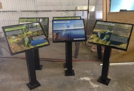 Three digital information display screens showing educational content about water and nature.