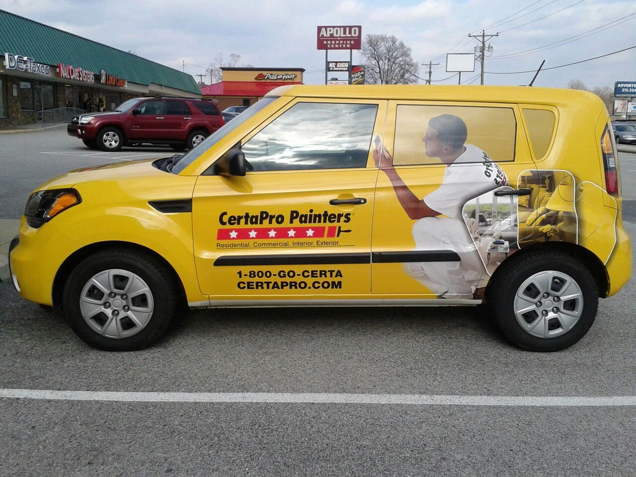 Yellow car with the CertaPro Painters logo and website, featuring a graphic of a painter squatting and painting the side of the vehicle.