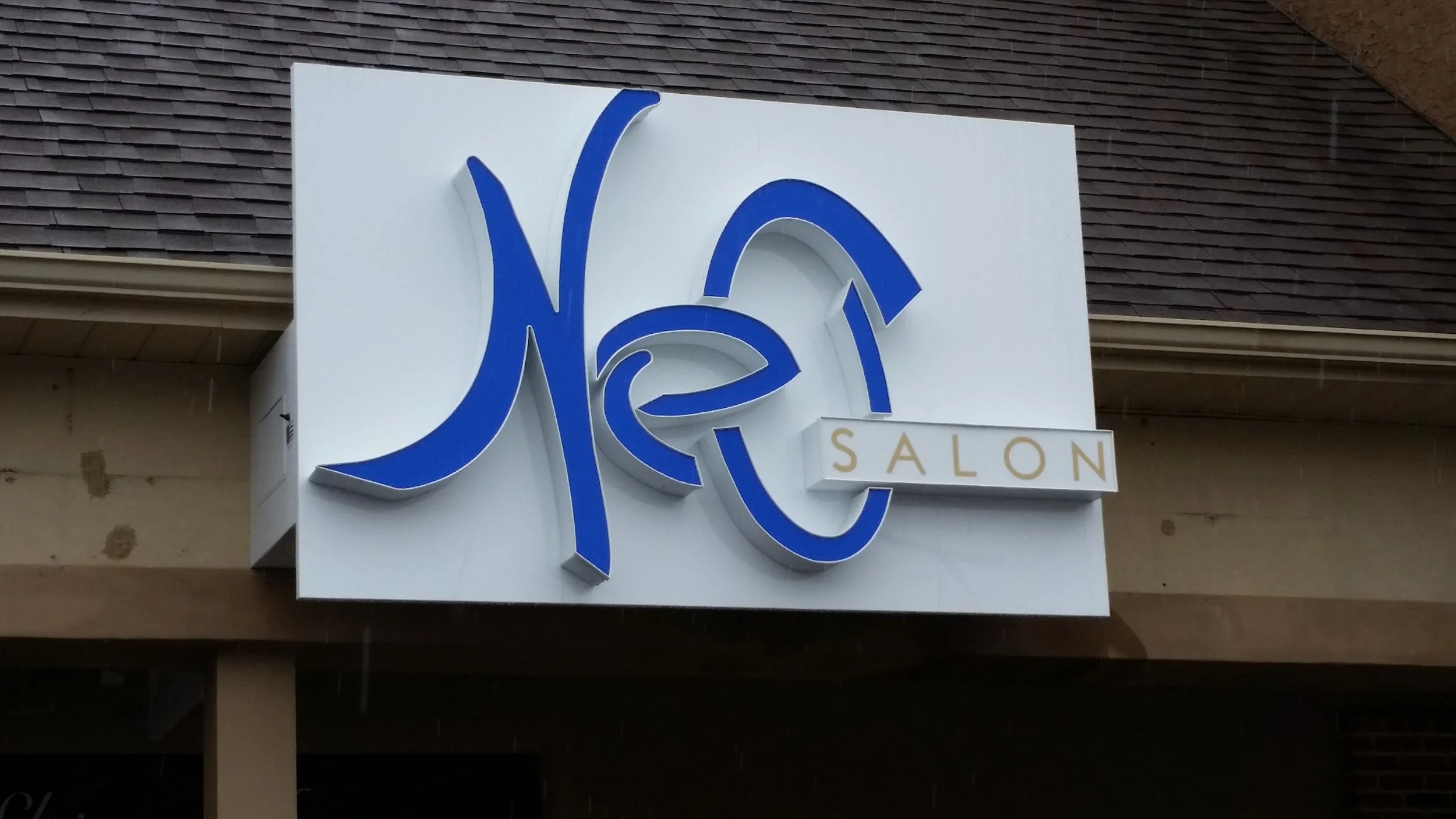 Sign for Ye's Salon with a white background and blue stylized text.
