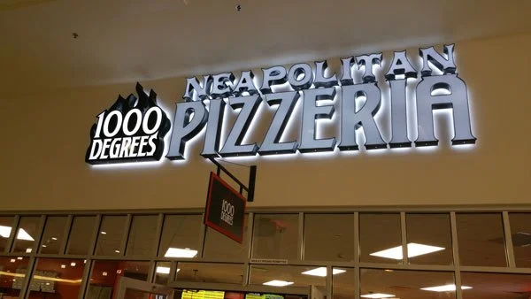 Neapolitan Pizzeria sign inside a shopping mall with the words '1000 Degrees' and 'Neapolitan Pizzeria' in large illuminated letters.