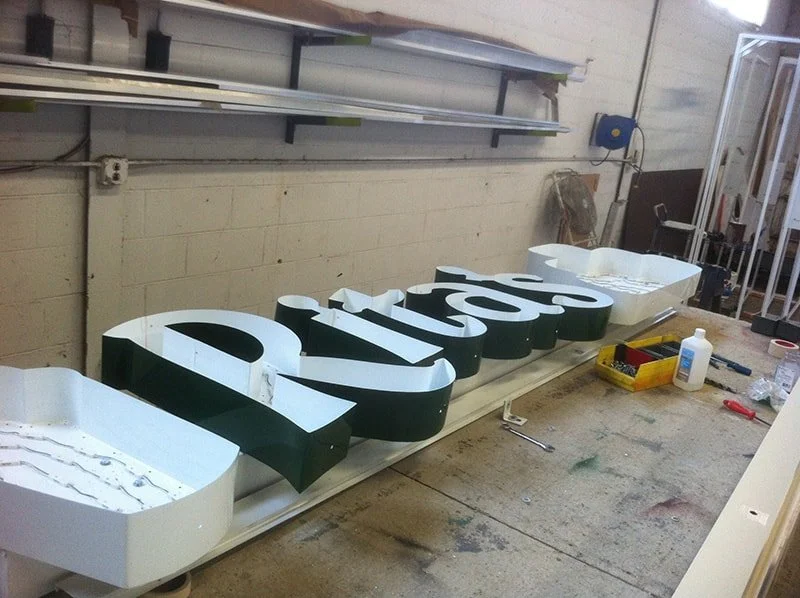 Large 3D sign with the text 'Atrios' being assembled on a workbench in a workshop