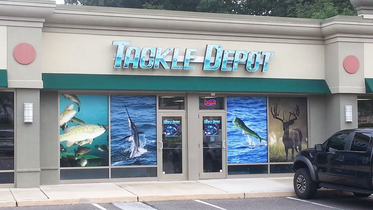 Front of a Tackle Depot store with large fishing-themed window graphics featuring fish and a deer