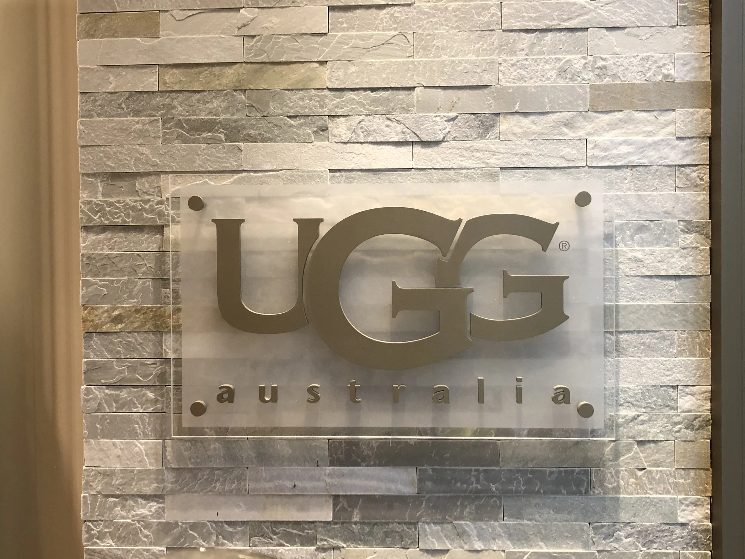 A transparent sign with text about an online marketing mission statement, mounted on a green wall.