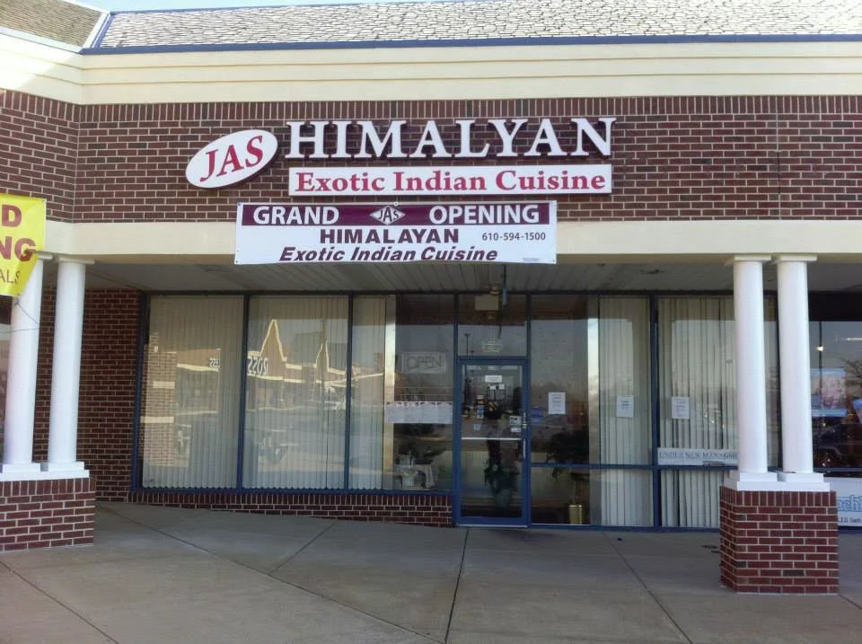The exterior of a restaurant named Himalyan, offering exotic Indian cuisine, with signs indicating it is open and announcing a grand opening.