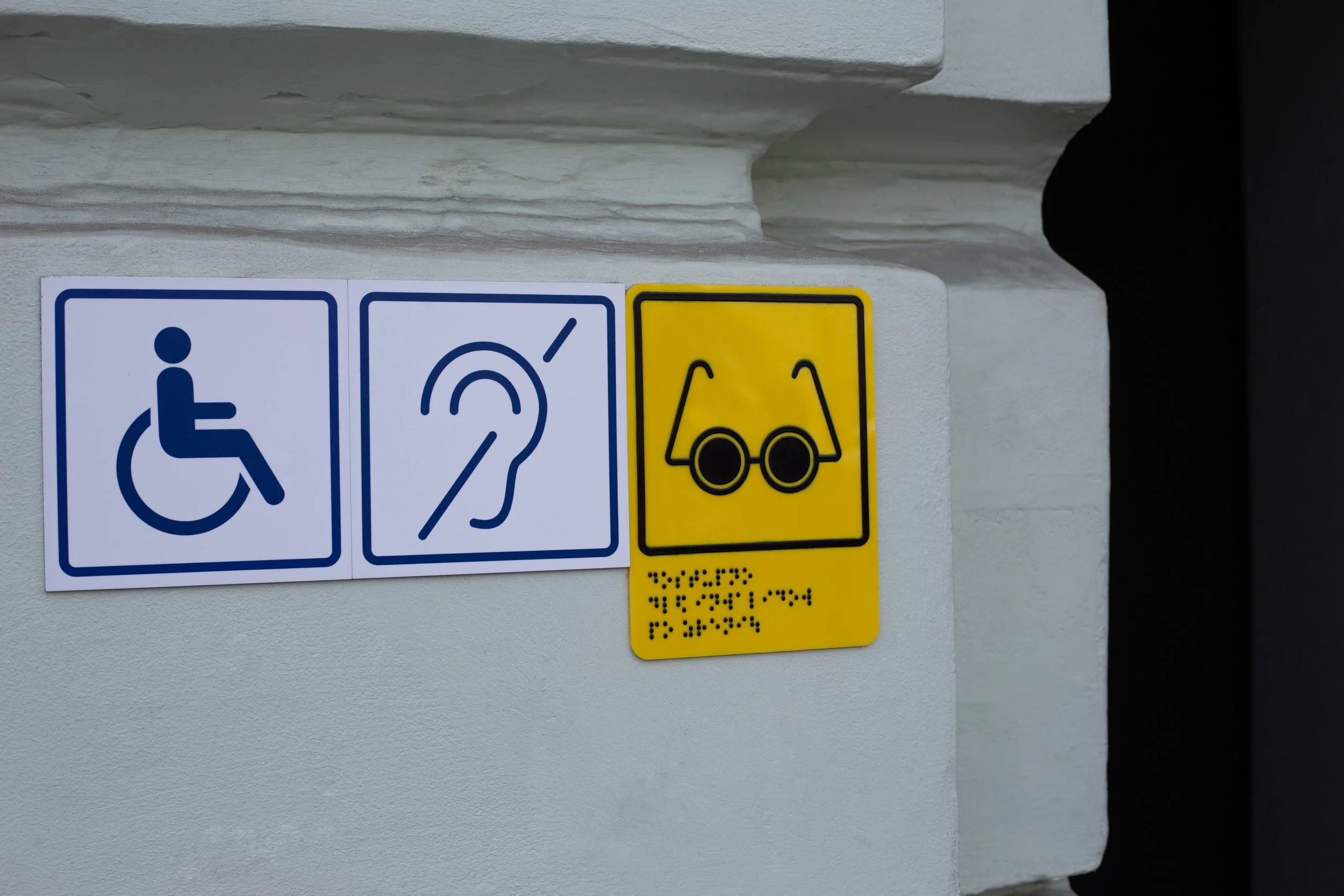 Signs indicating accessible parking, hearing impairment assistance, and wheelchair transportation.