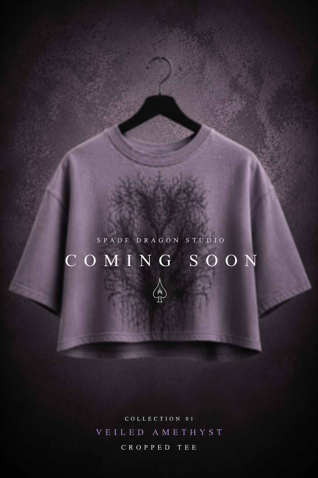 A cropped purple t-shirt with a black tree design, hanging on a black hanger against a textured dark background. Overlaid text says "COMING SOON" for Spade Dragon Studio, with additional details about the collection and product.