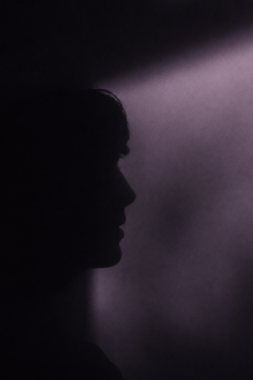Silhouette of a person's profile against a purple and black background.