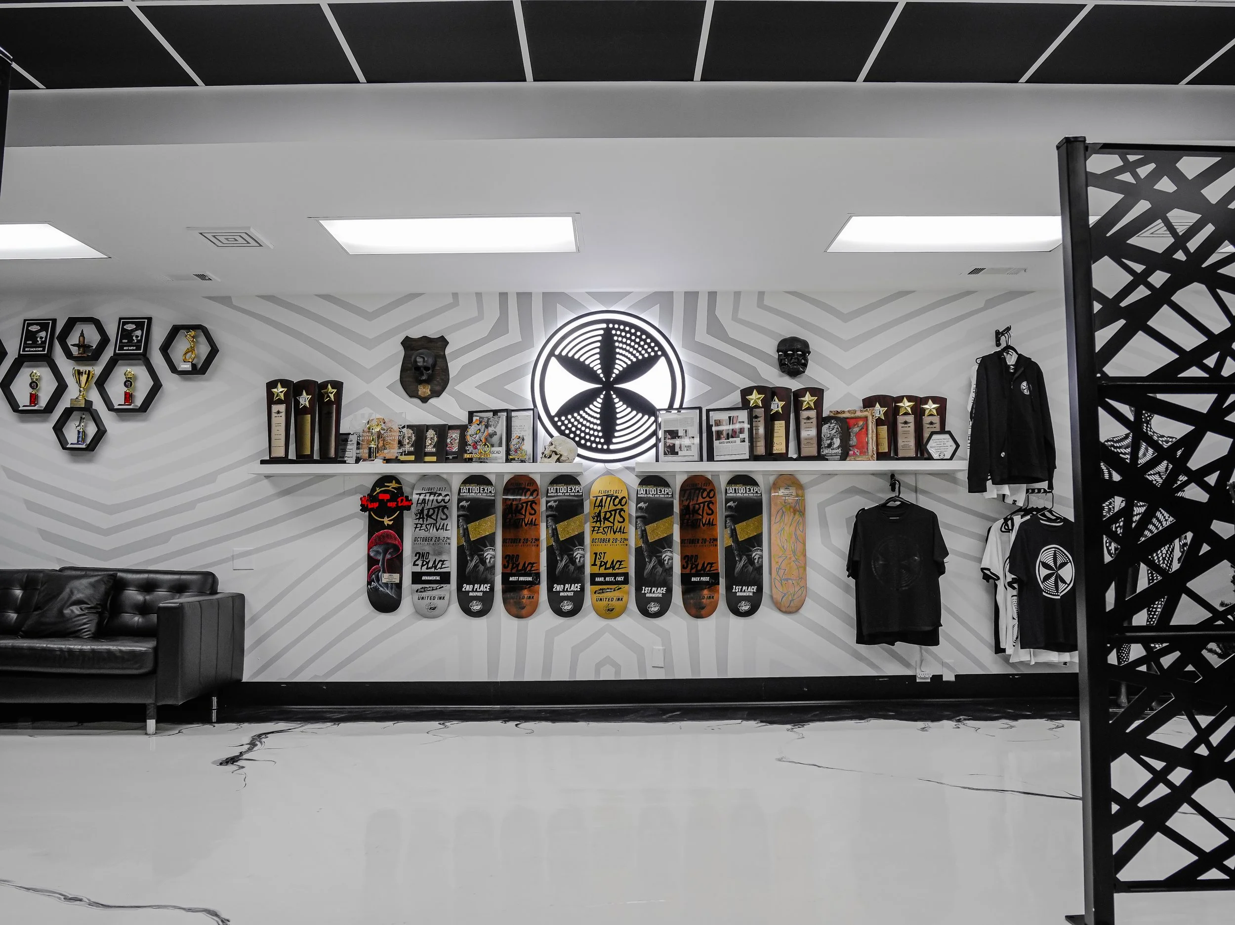 Display of skateboards, trophies, and clothing on a wall in a trophy shop or skate shop with black and white decor.