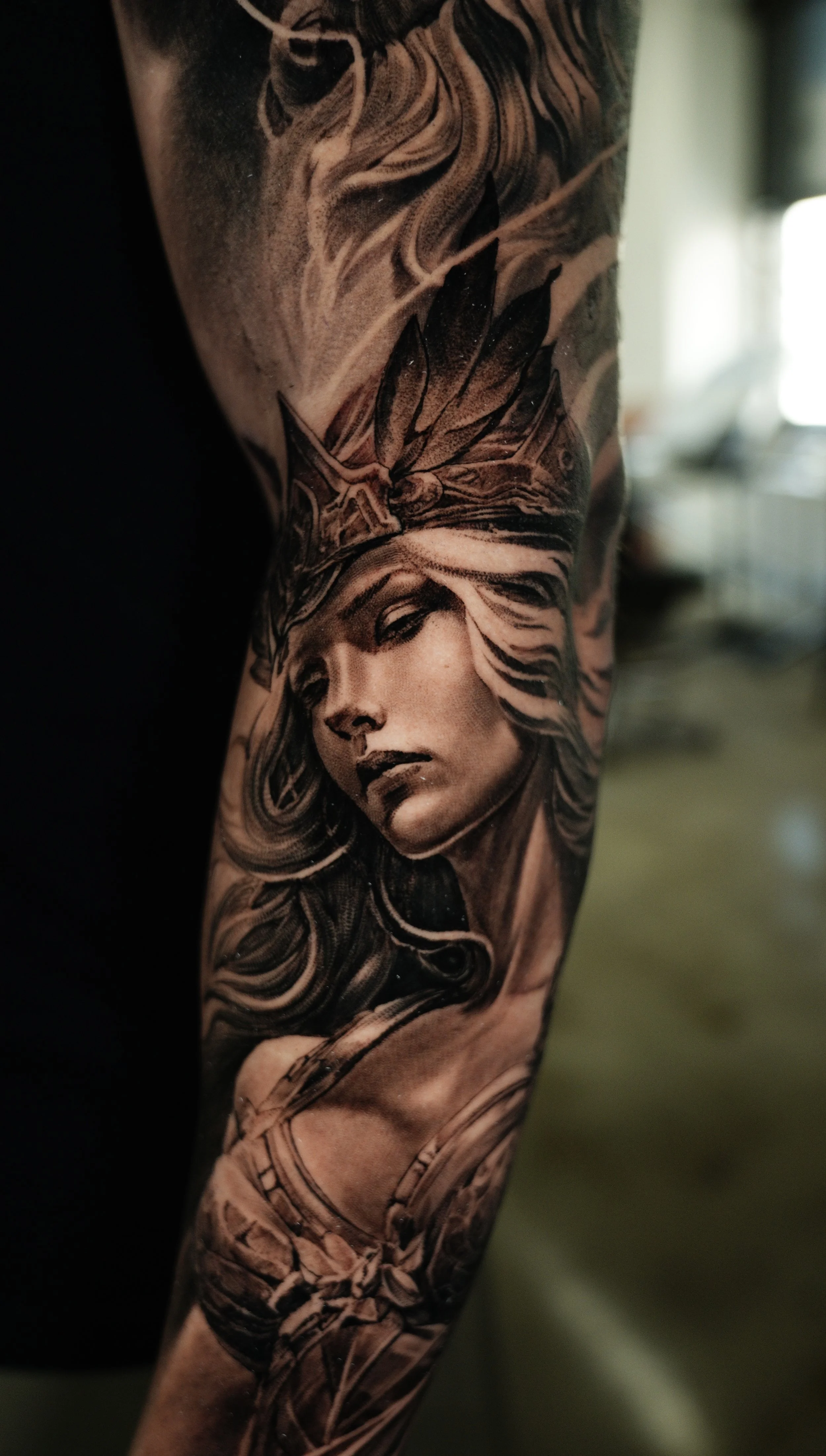 Close-up of a tattoo on a person's arm depicting a woman's face with long flowing hair and a crown.