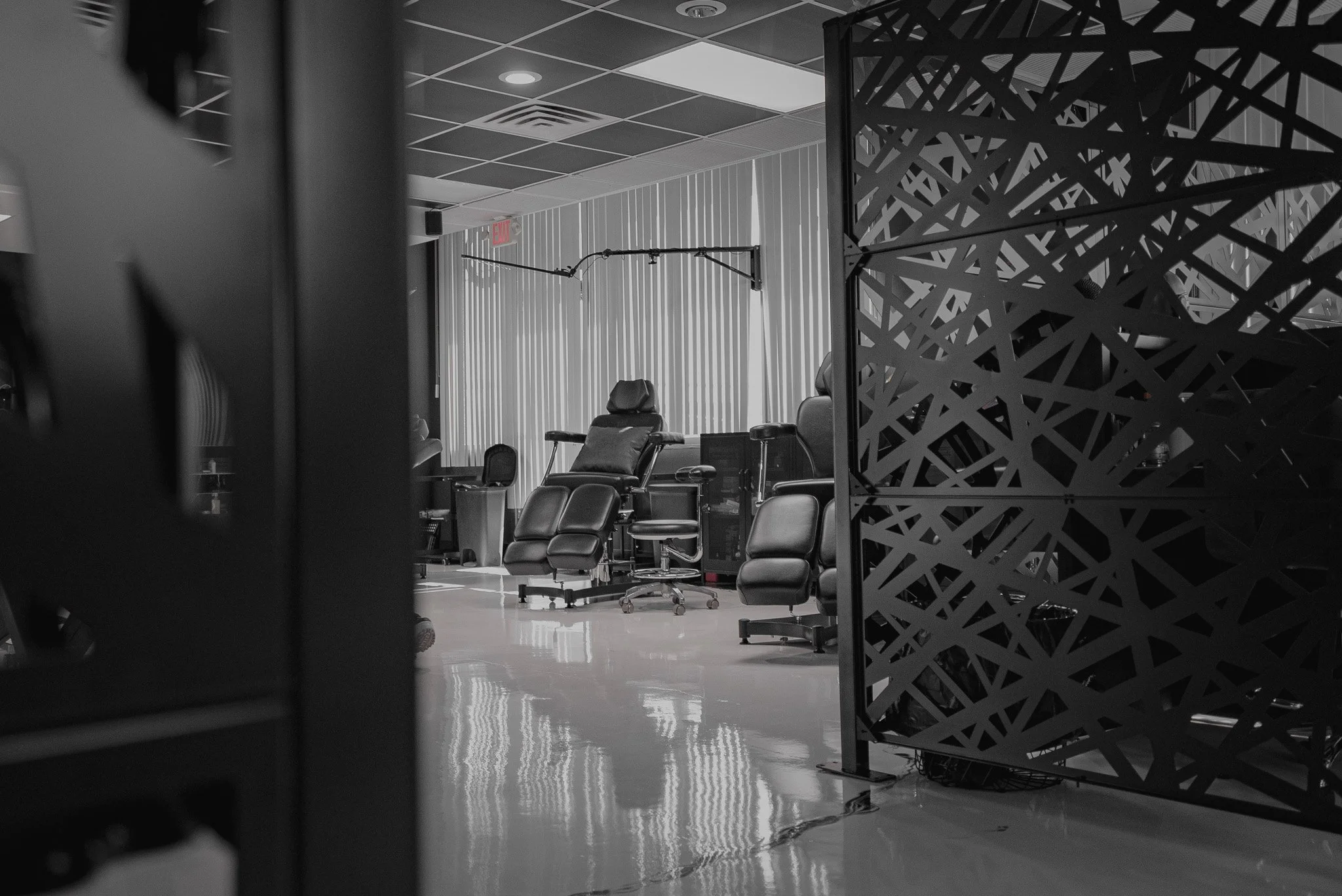 Empty medical or dental office with chairs and equipment, black and white, modern interior with grid ceiling and vertical blinds.