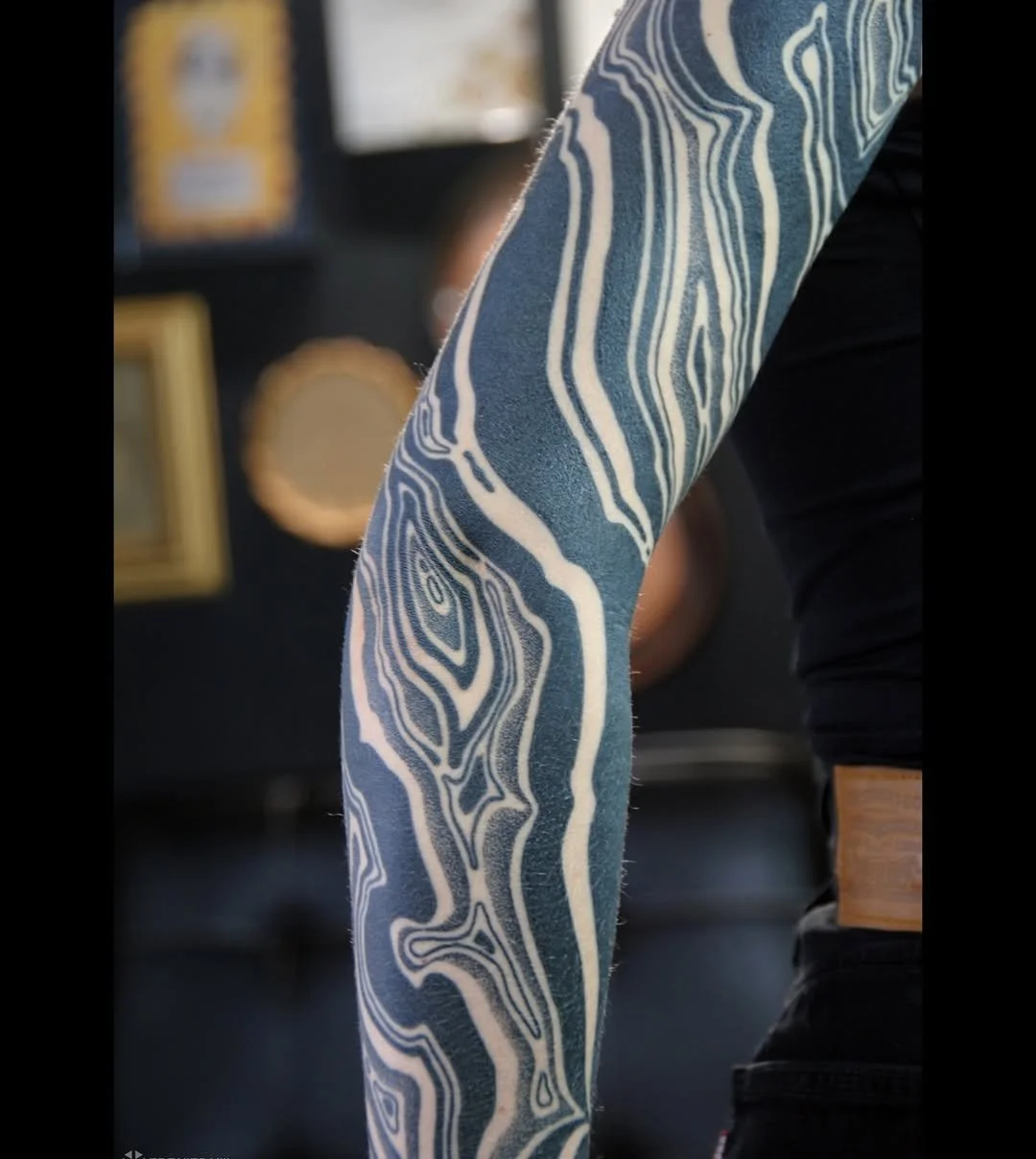 Close-up of a person's arm with blue and white marble pattern tattoo.