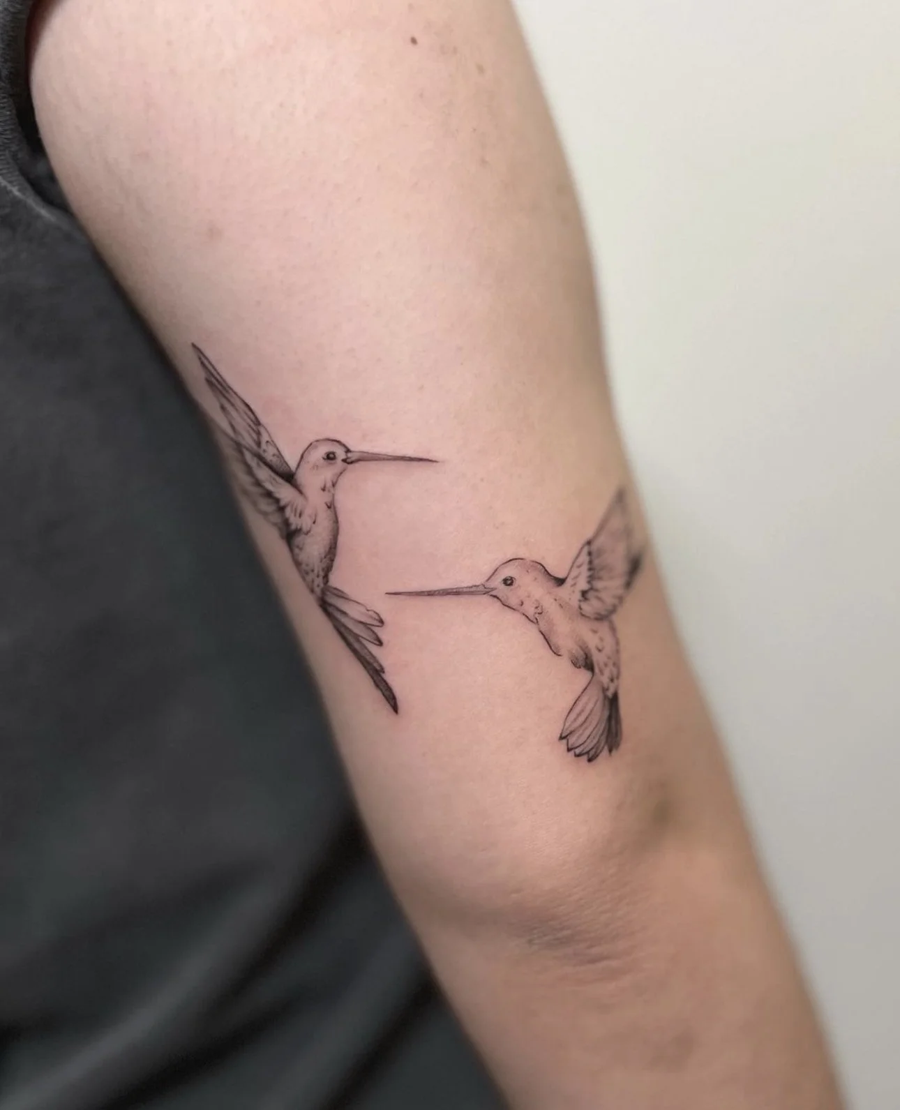 Tattoo of two hummingbirds facing each other on an arm.
