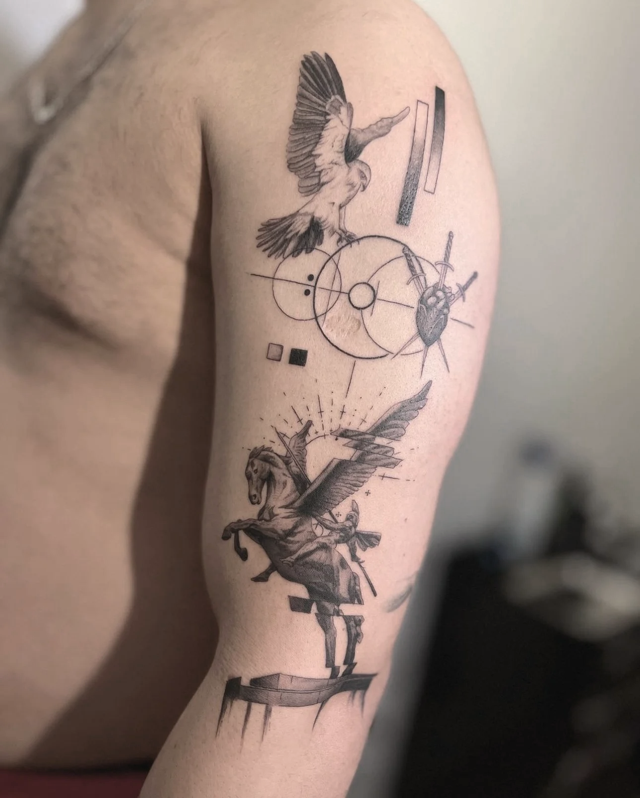 Tattoo of a flying horse with swords and geometric shapes on the upper arm.