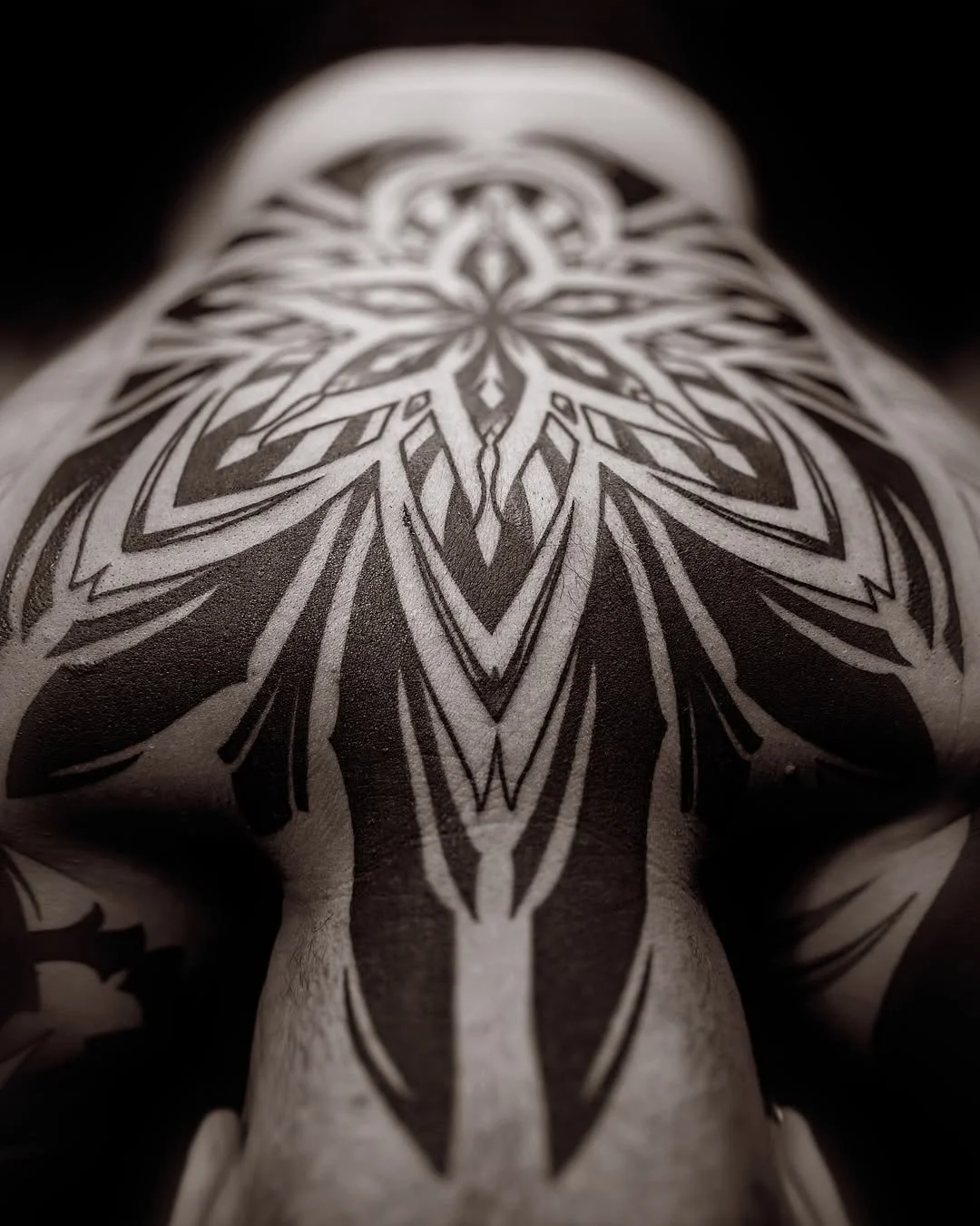 Close-up of a black tattoo design with symmetrical, geometric patterns on skin.