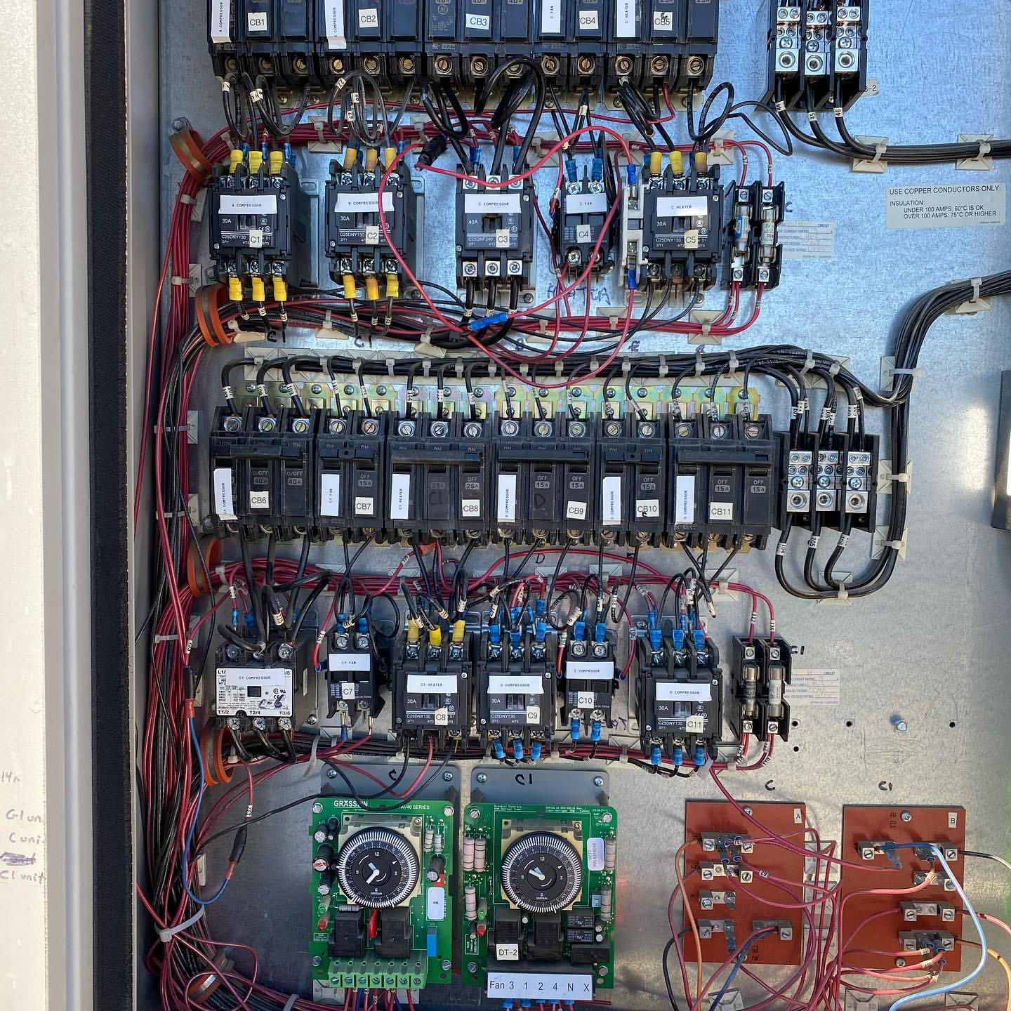 An electrical control panel with various circuit breakers, wires, and gauges.