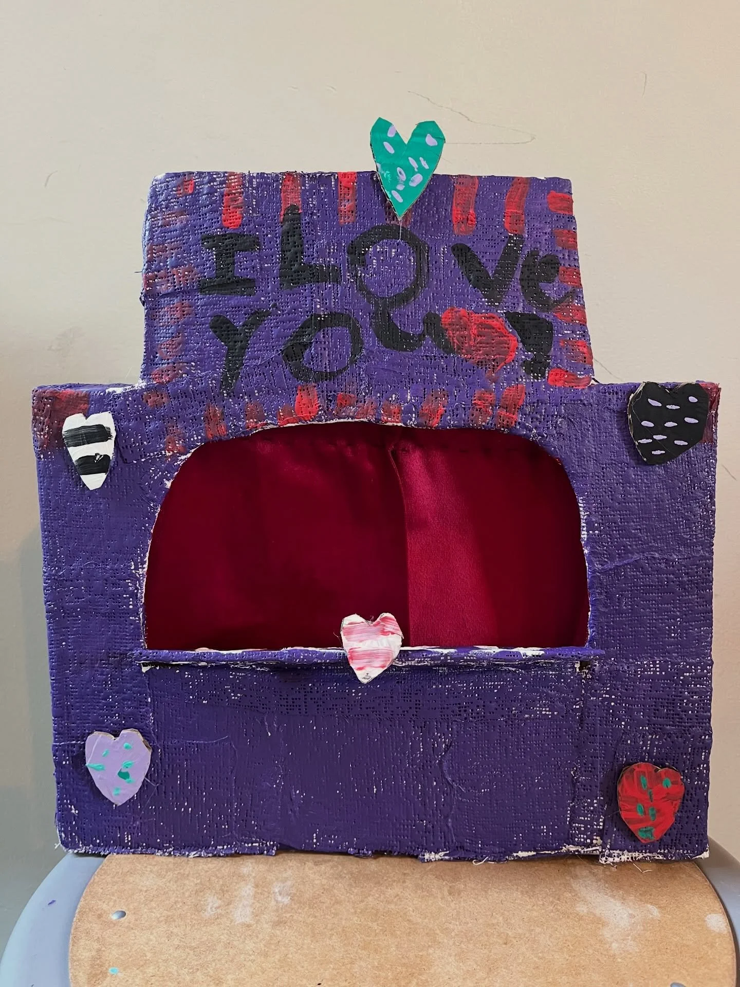 Puppet theaters made from recycled boxes, cardboard scraps, masking tape, plaster cloth, acrylic paint. Curtains made from velvet scraps draped on found sticks.