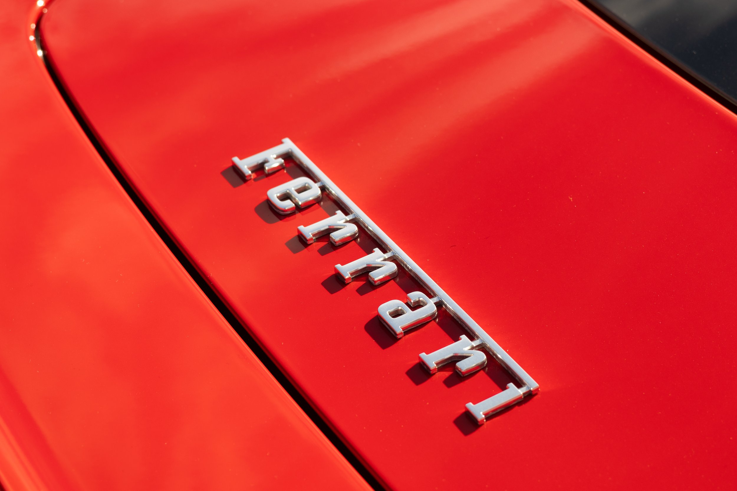Close-up of a red Ferrari car with the silver Ferrari emblem on the hood. Car meet. Cars and coffee. Rollers. Stills. Detail shots. Brand awareness. Ferrari 458.