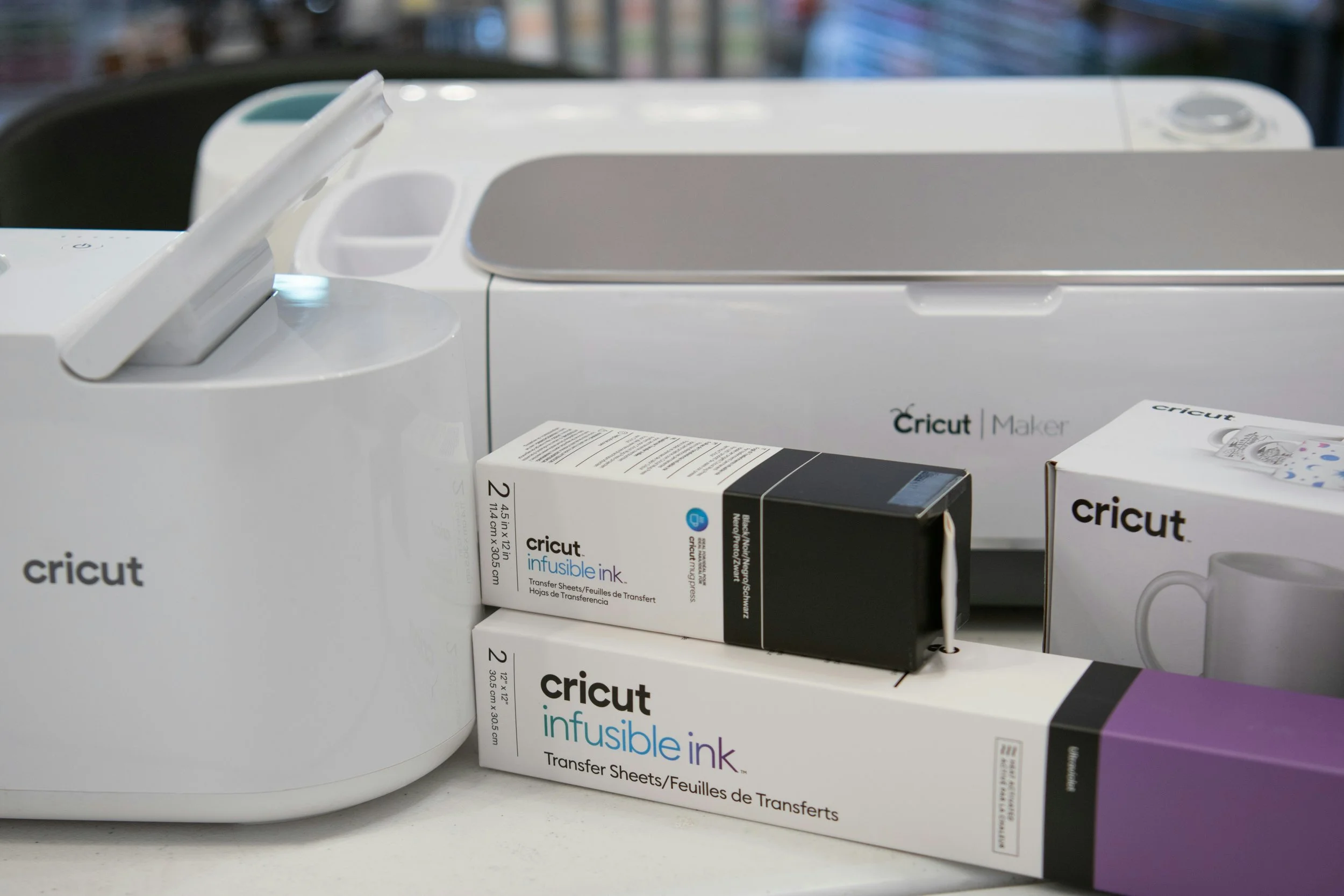The image shows a Cricut cutting machine with a box of Cricut infusible ink transfer sheets placed in front of it.