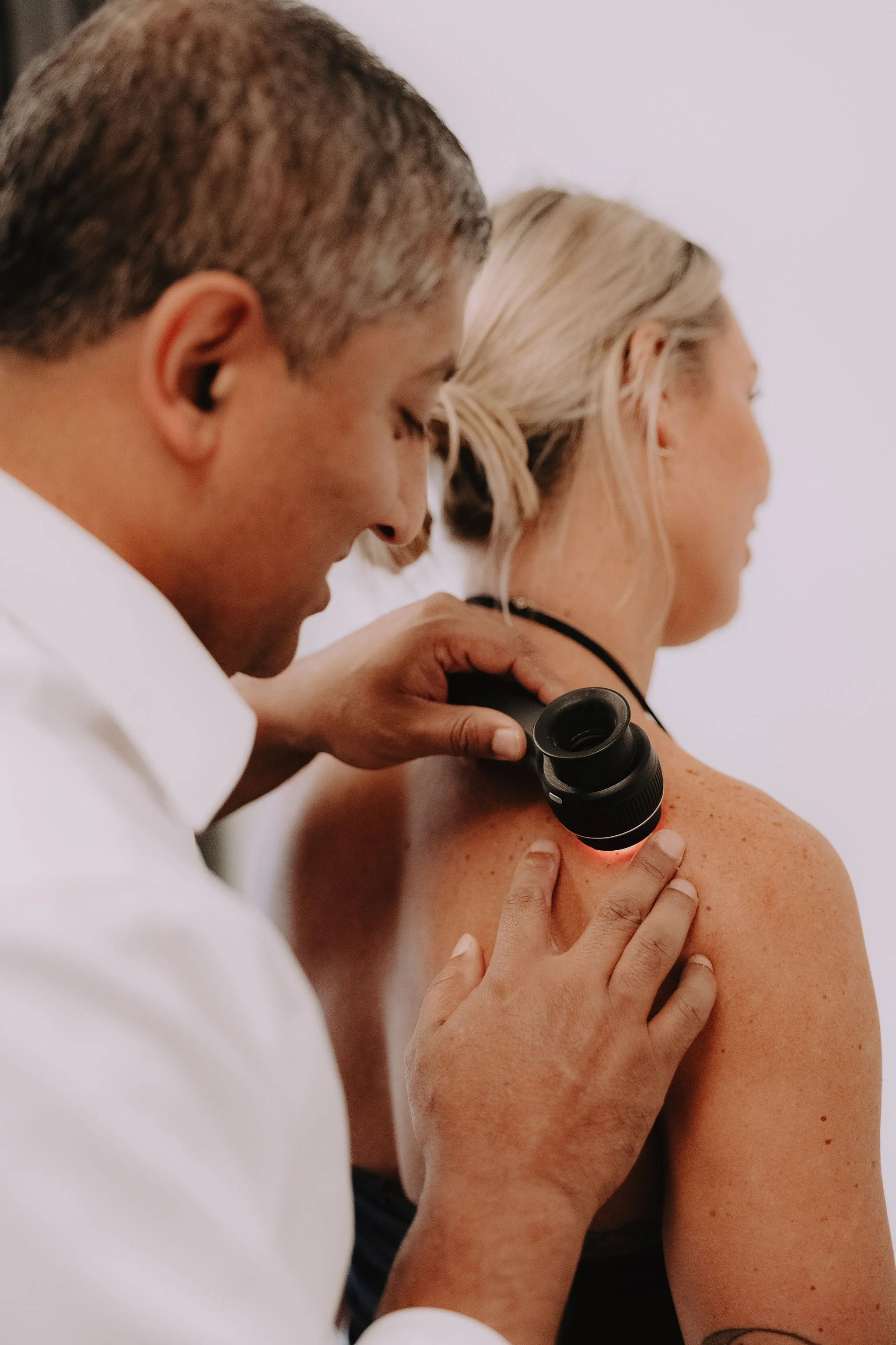 Doctor examining a woman's shoulder with a device.