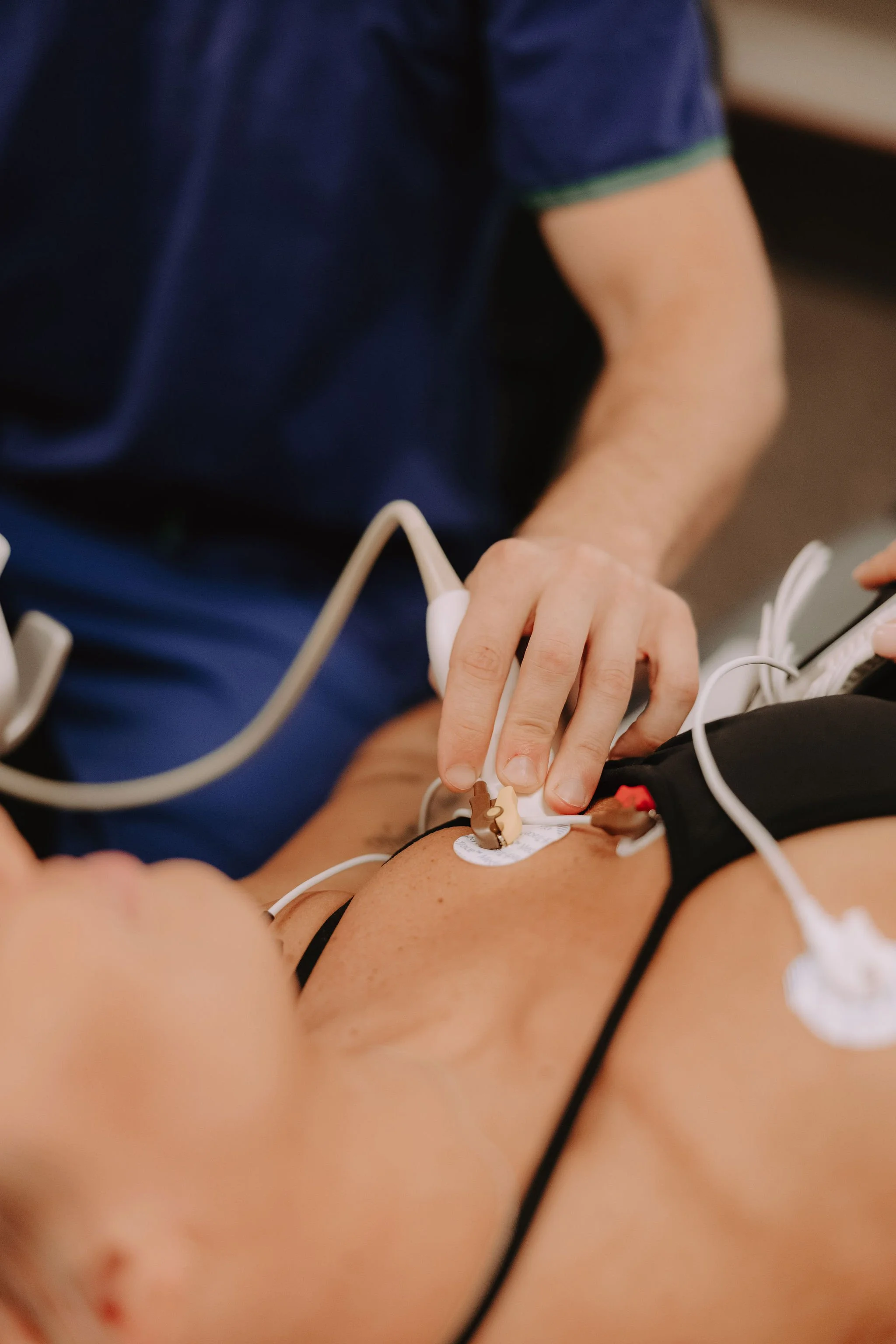 A healthcare professional performs an electrocardiogram (ECG) on a patient by attaching electrodes to the chest.